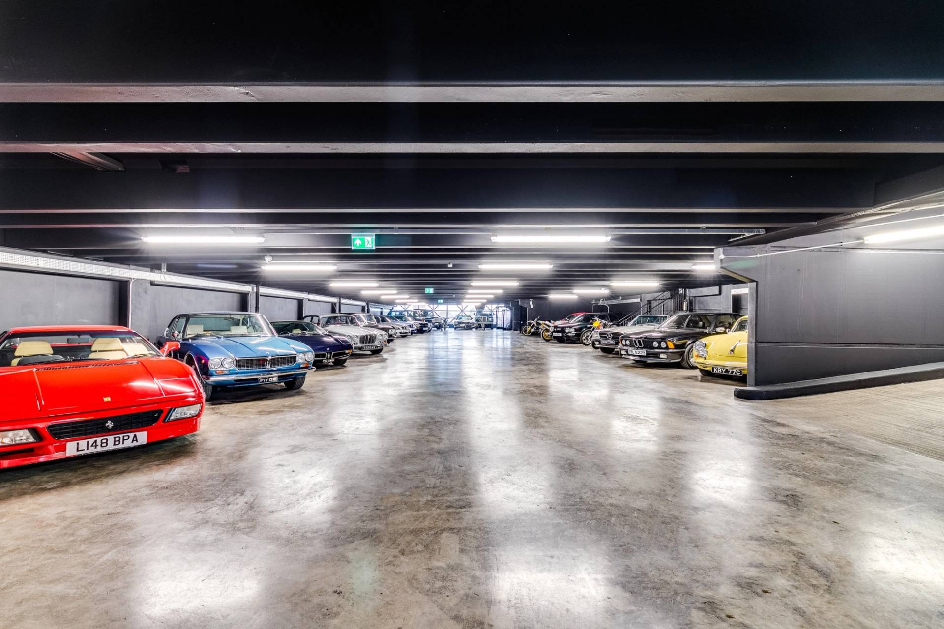 Open showroom floor with classic cars parked in rows under industrial LED lighting through Love Locations.