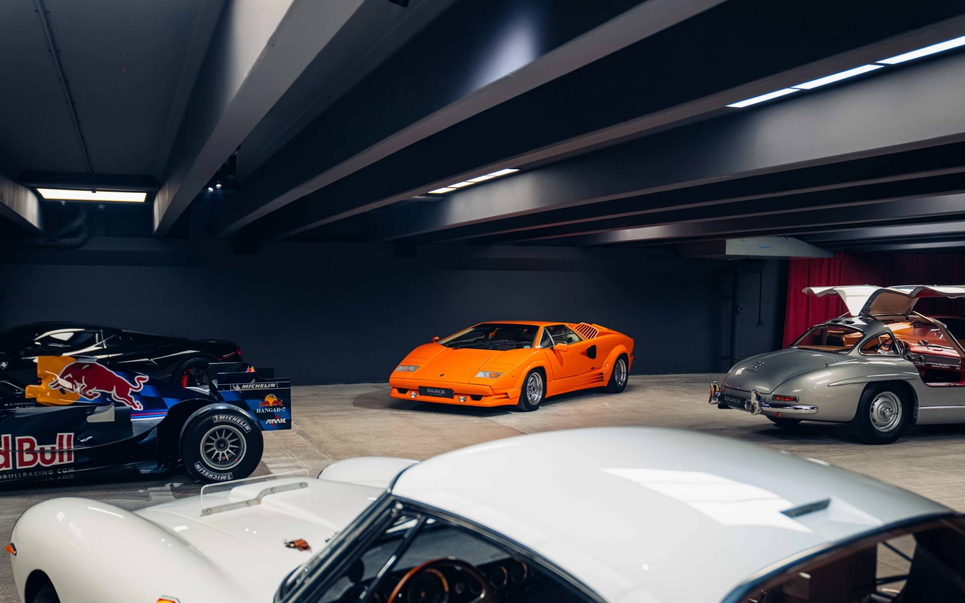 Orange classic sports car parked on polished concrete in a dark industrial basement location via Love Locations.