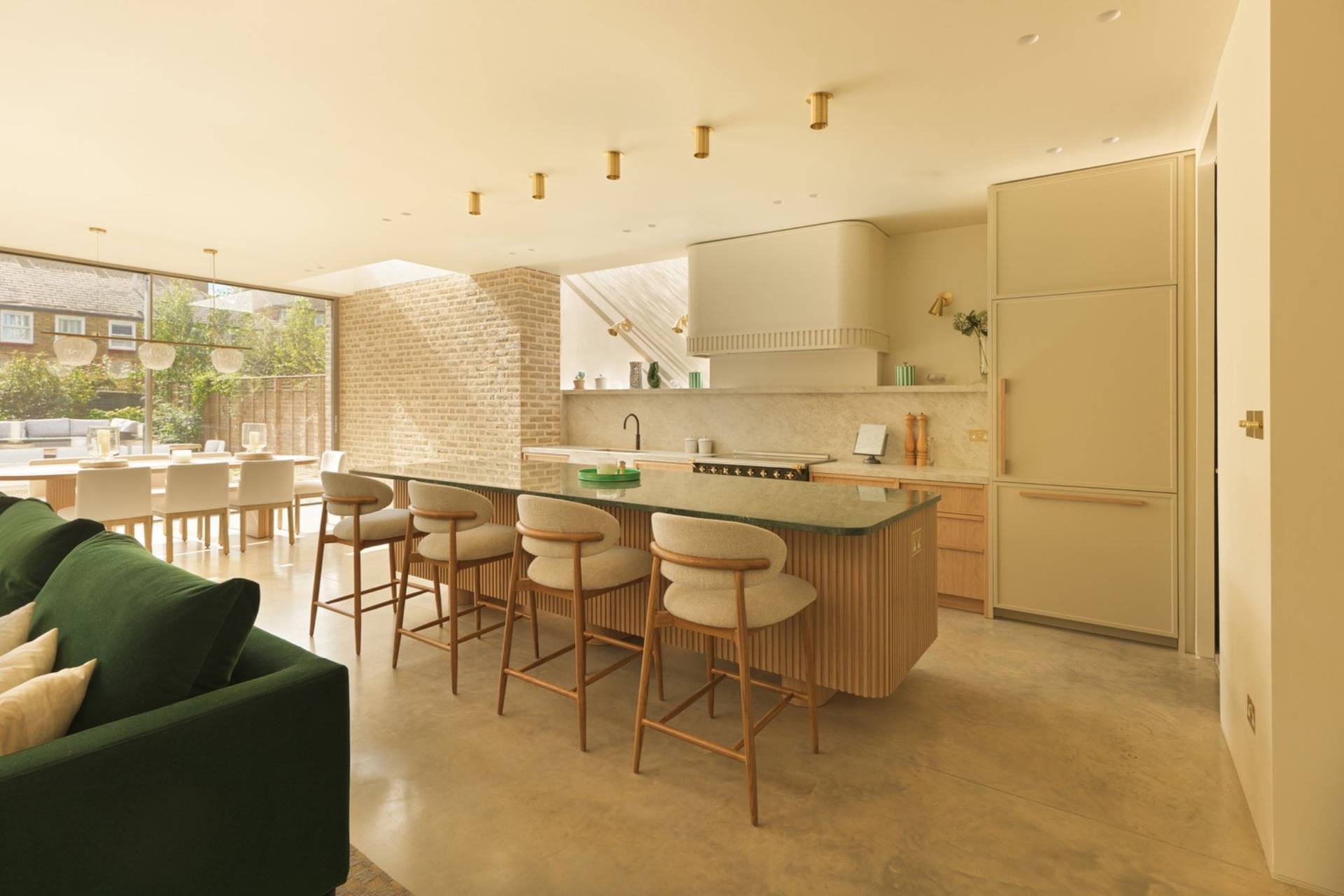 Architectural kitchen shoot space in Clapham South SW11 via Love Locations, showcasing a ribbed timber island with green marble countertop, high bar stools, and minimalist cabinetry.
