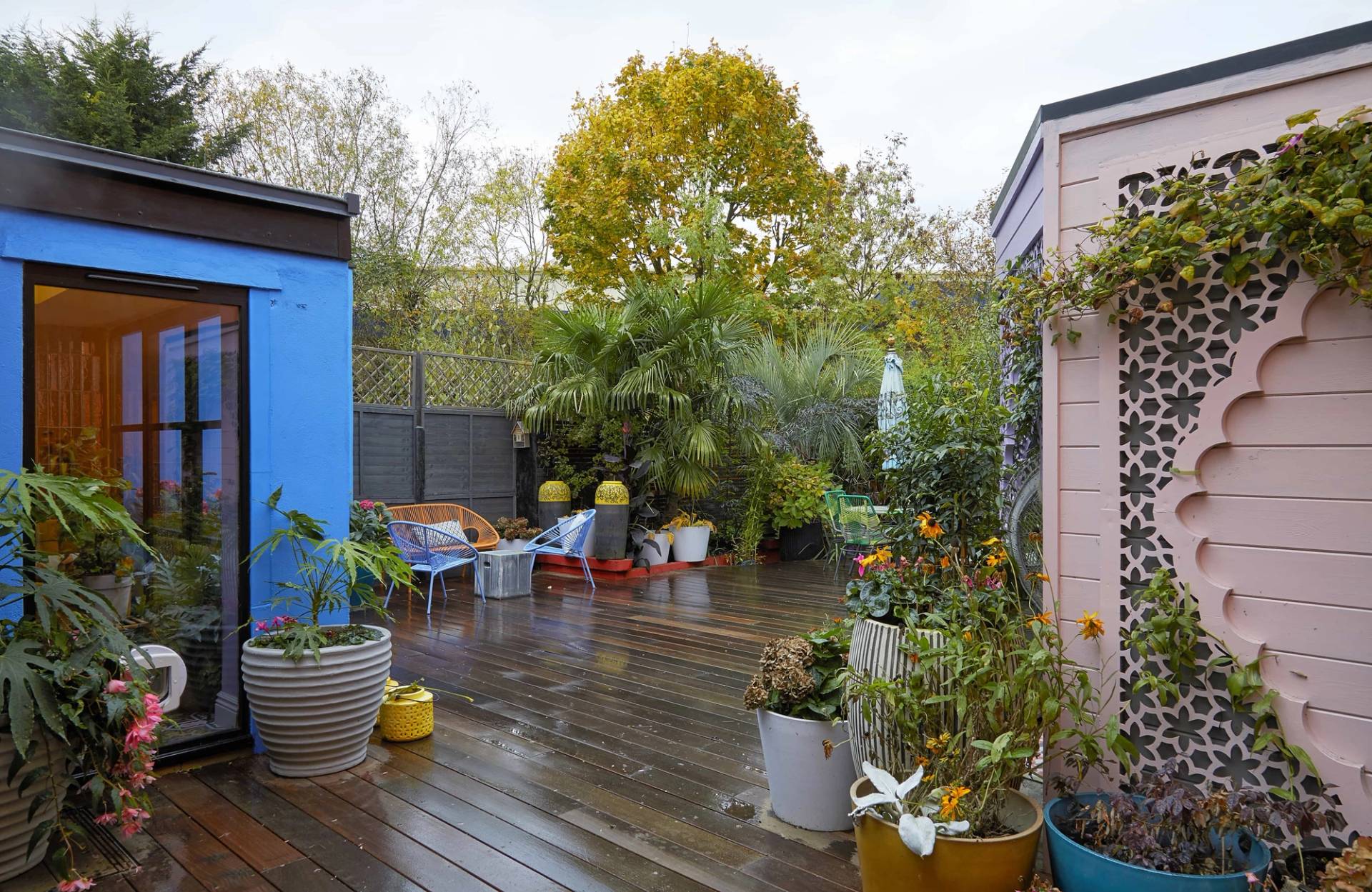 Wide timber garden decking terrace with potted plants, outdoor seating, and colorful house exterior facades, Love Locations Catford.