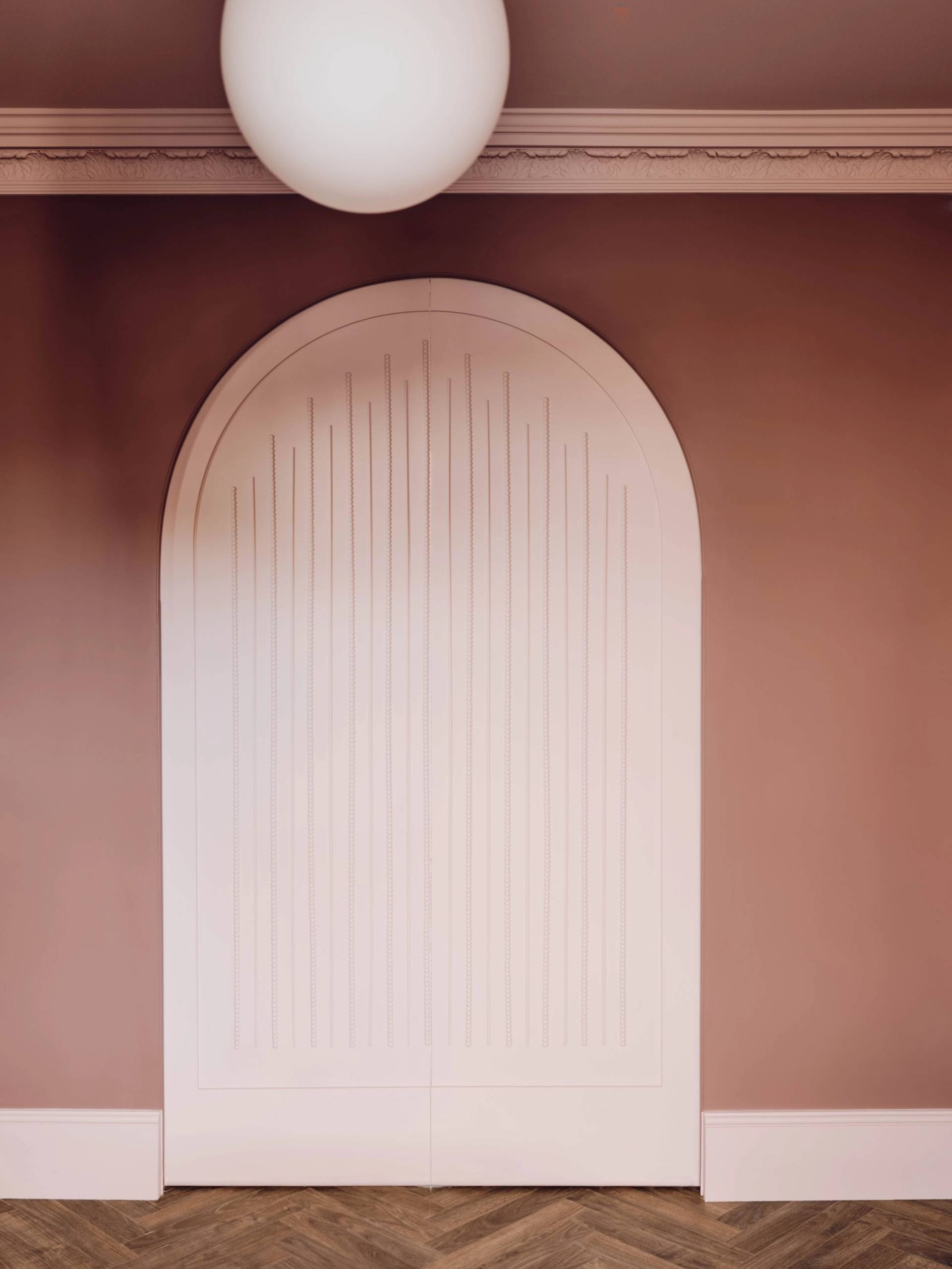 Close-up of a bespoke pink arched door panel showing vertical groove details, Love Locations CR0.