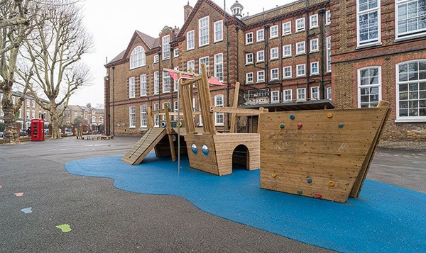 Children's playground shoot space featuring a modern wooden pirate ship play structure and blue safety flooring, Love Locations.