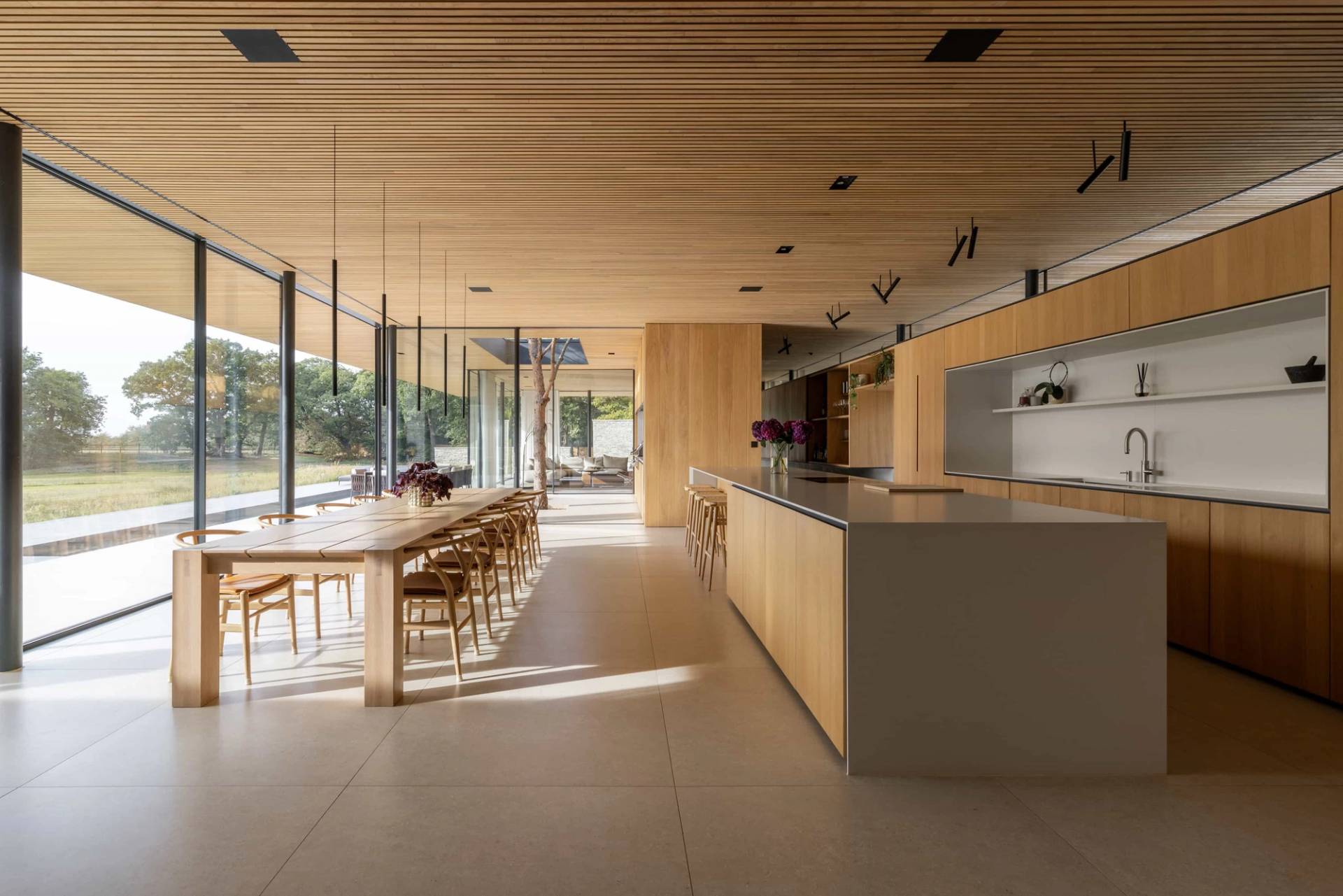 Modern minimalist new build kitchen and dining shoot location in Fryerning, CM4 featuring sleek architectural lines, wooden slatted ceilings, and expansive glazing, ideal for luxury lifestyle brand campaigns via Love Locations.