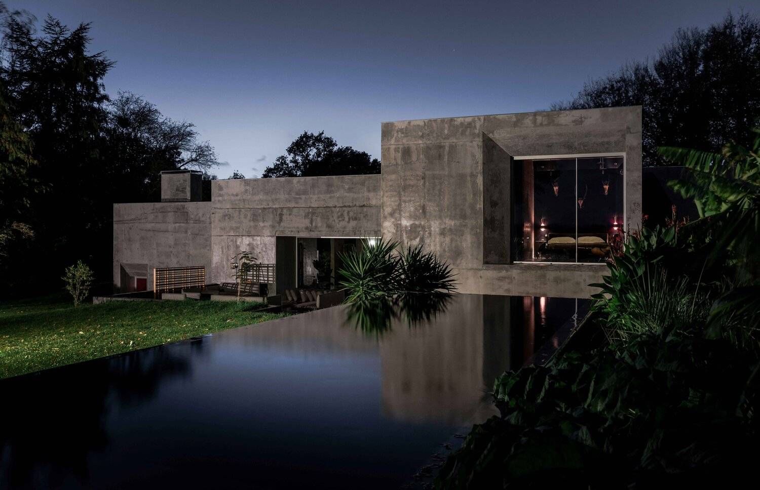 Brutalist architectural location home hero cover image in Plumpton Green, BN7 featuring board-marked concrete facade, natural swimming pond, internal jungle planter walls, mid-century furnishings, and expansive Sussex grounds, the ultimate high-visibility backdrop for luxury brand campaigns, TV commercials, automotive ads, feature film productions, and editorial photography via Love Locations.