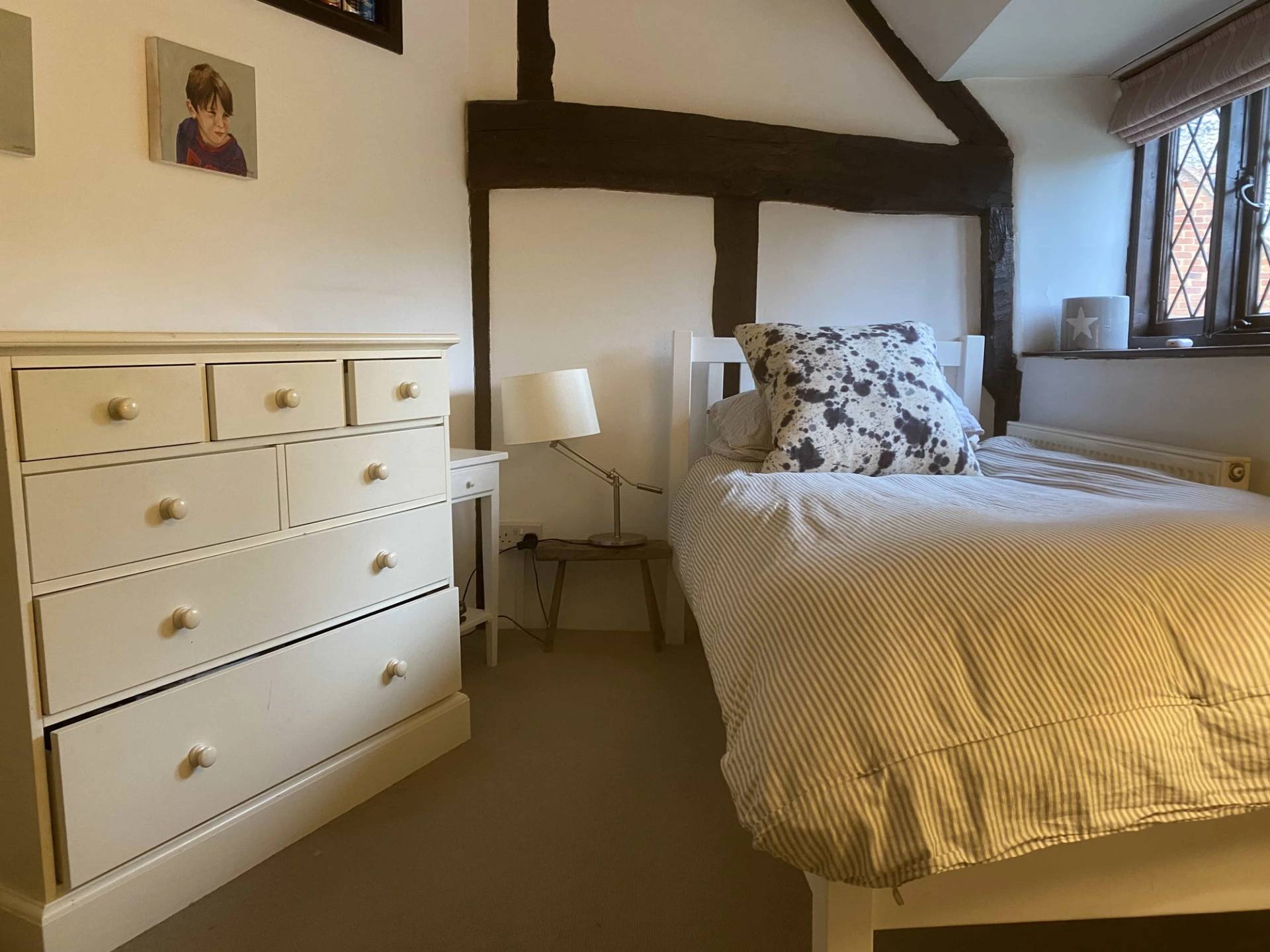 Bright character bedroom setup with a white wooden chest of drawers and exposed structural oak framing, ideal for lifestyle brand shoots, Love Locations.