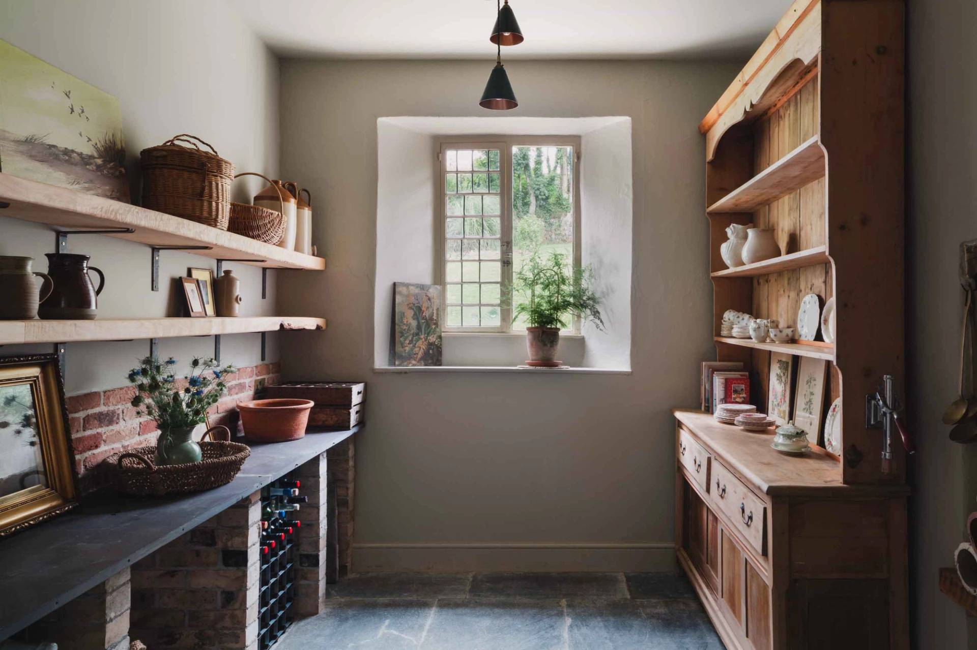 Larder room with slate floors, stone walls, and rustic wooden shelving in Newquay Cornwall via Love Locations.