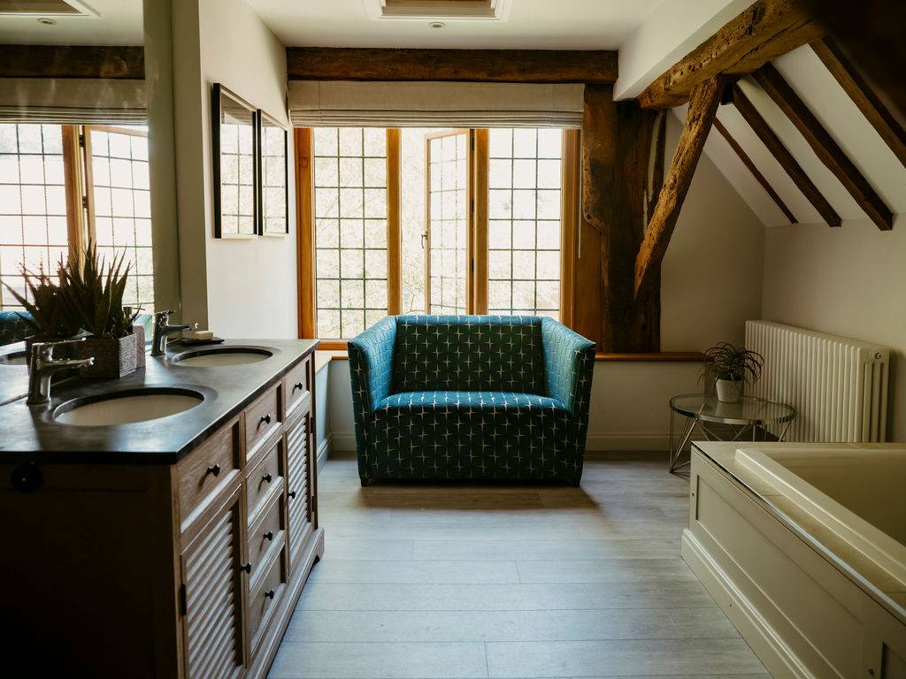 Luxury ensuite bathroom featuring a dark wood double sink vanity and freestanding soaking tub under exposed beams, perfect for wellness product advertising, Love Locations RG9.