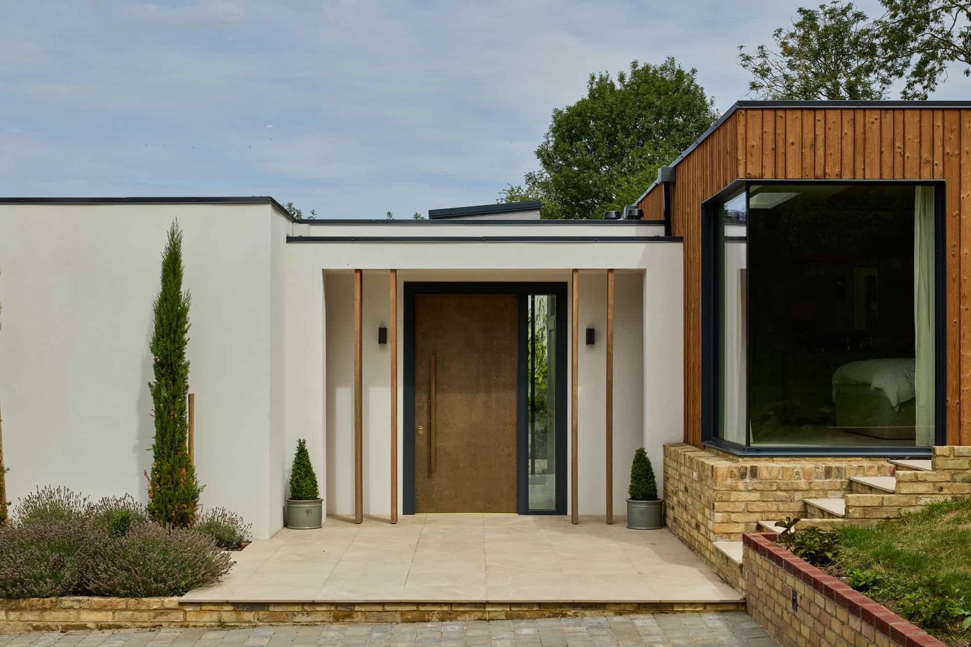 Modern entrance portico with a tall wooden front door, white renders, and timber vertical louvres, perfect for high-end film establishing shots, Love Locations.