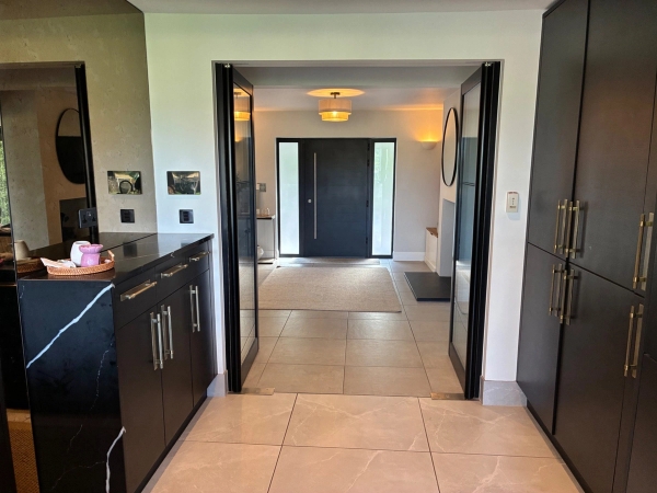 Grand interior entrance hall and corridor in Essex CM4 by Love Locations, featuring black-framed glass double doors and clean neutral tile flooring.