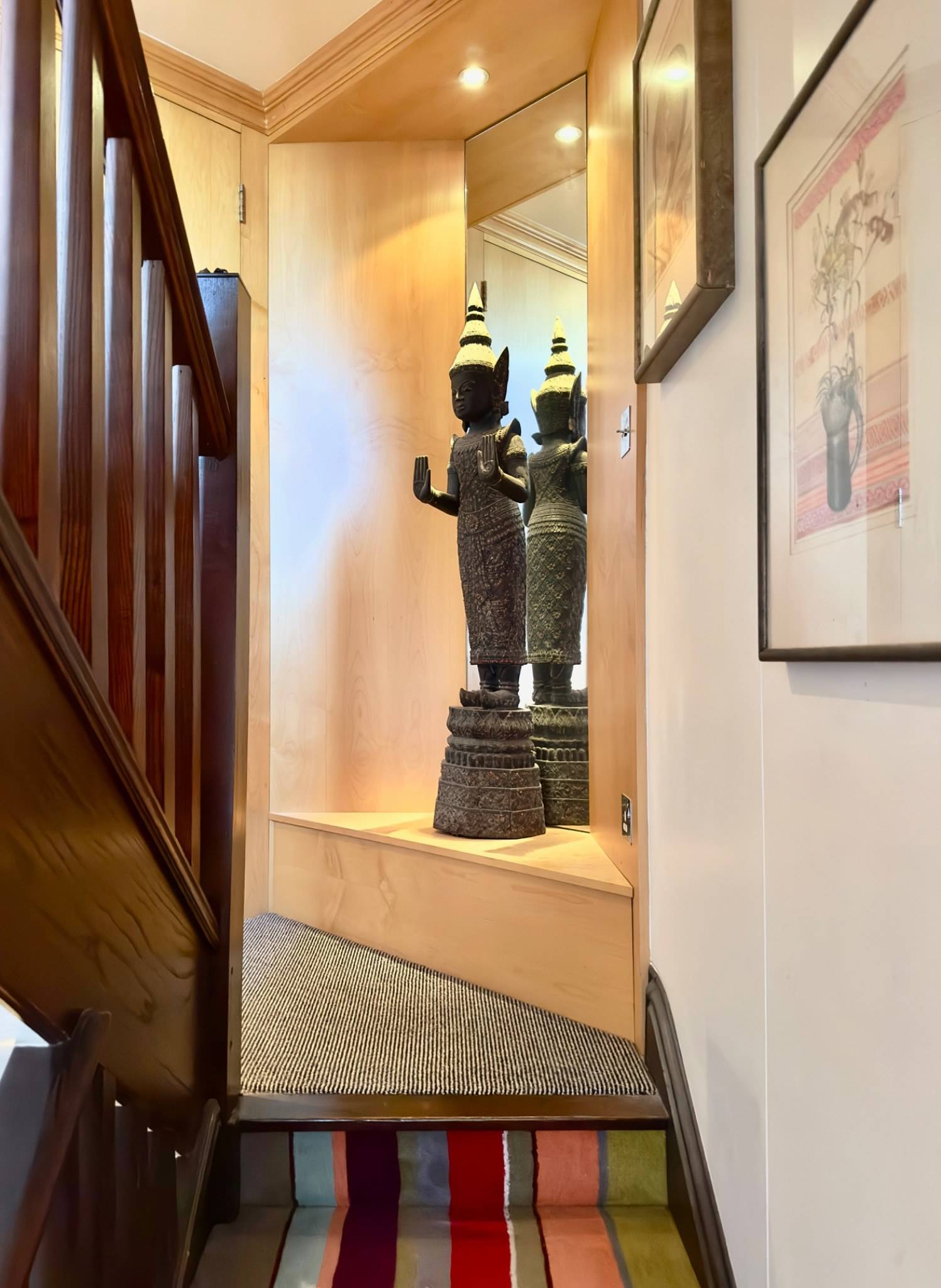 Wooden staircase and landing display featuring Asian sculptural art pieces in a South London location property by Love Locations.
