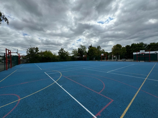 Love Locations blue hardstanding court location EN4: Expansive outdoor sports arena showing a striking blue surface layer and tennis or netball line work, optimized for commercial video.