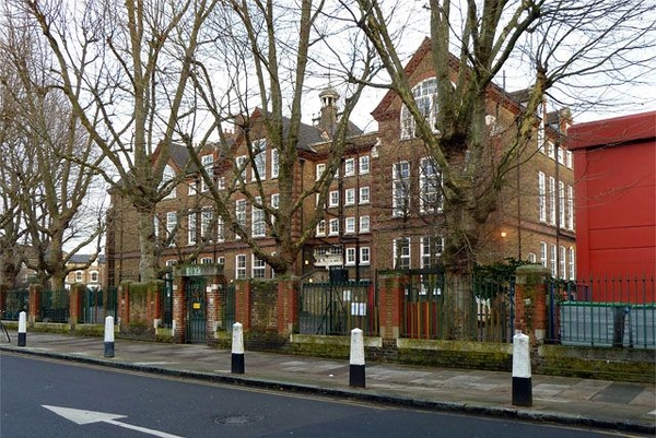 Traditional Victorian primary school exterior facade behind roadside trees in Finsbury Park, N4, a classic filming location via Love Locations.