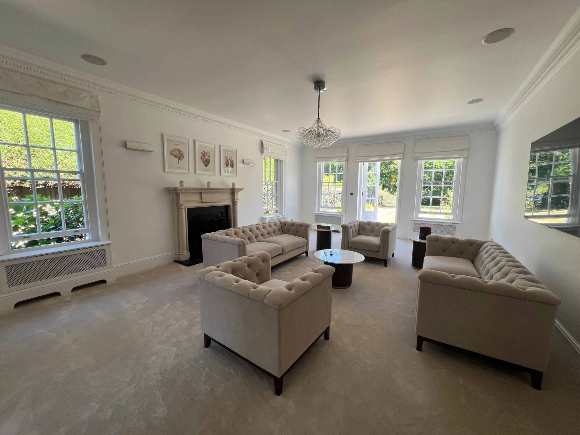 Bright living room suite with cream sofa seating, stone fireplace, and views over manicured gardens, Love Locations BR7.