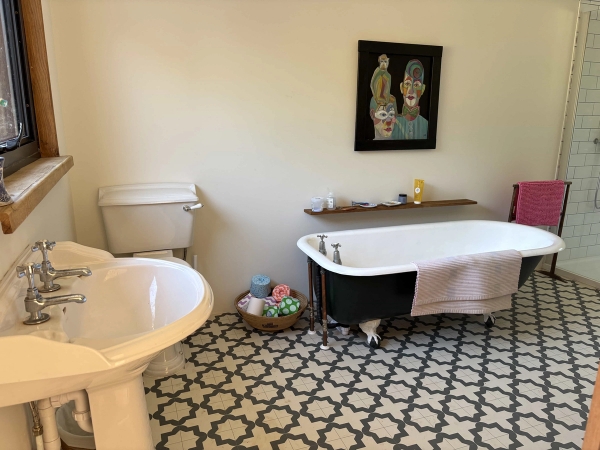 Vintage bathroom location with a freestanding roll-top clawfoot bath and patterned geometric floor tiles, Love Locations BN8.