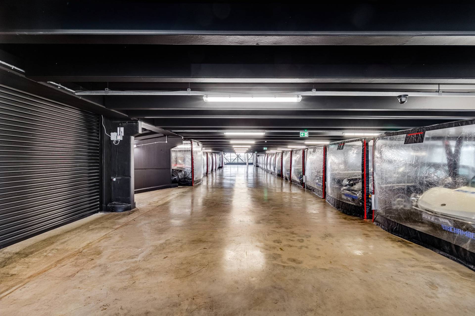 Clean industrial car storage hall with black ceiling beams in a West London production venue through Love Locations.