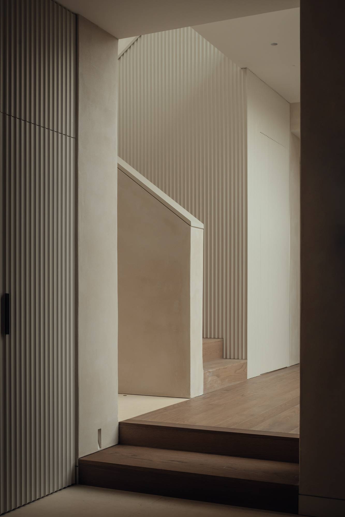 Architectural stairwell landing showcasing vertical fluted wall textures and a clean-lined modern staircase design, ideal for high-end design lookbooks, Love Locations SO20.