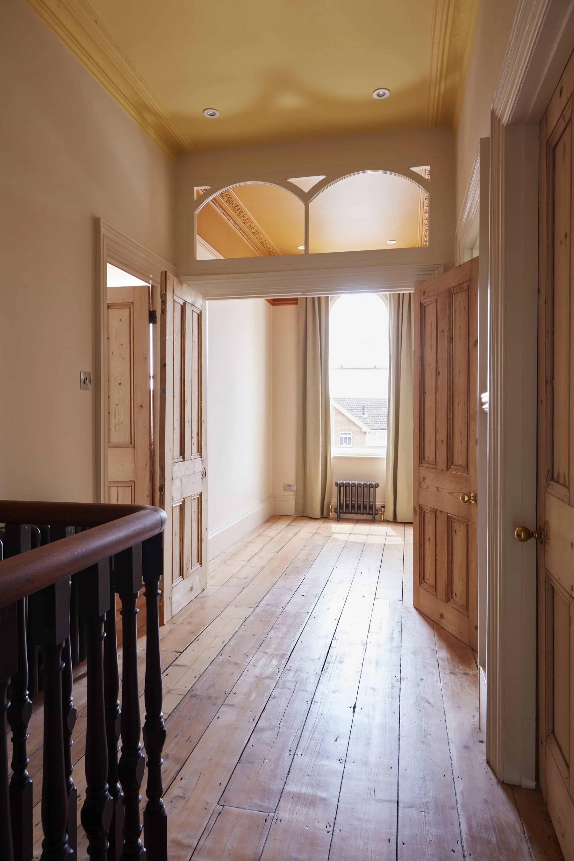 Upper hallway landing with dark wood balustrades and natural light through high sash windows, Love Locations TN34.