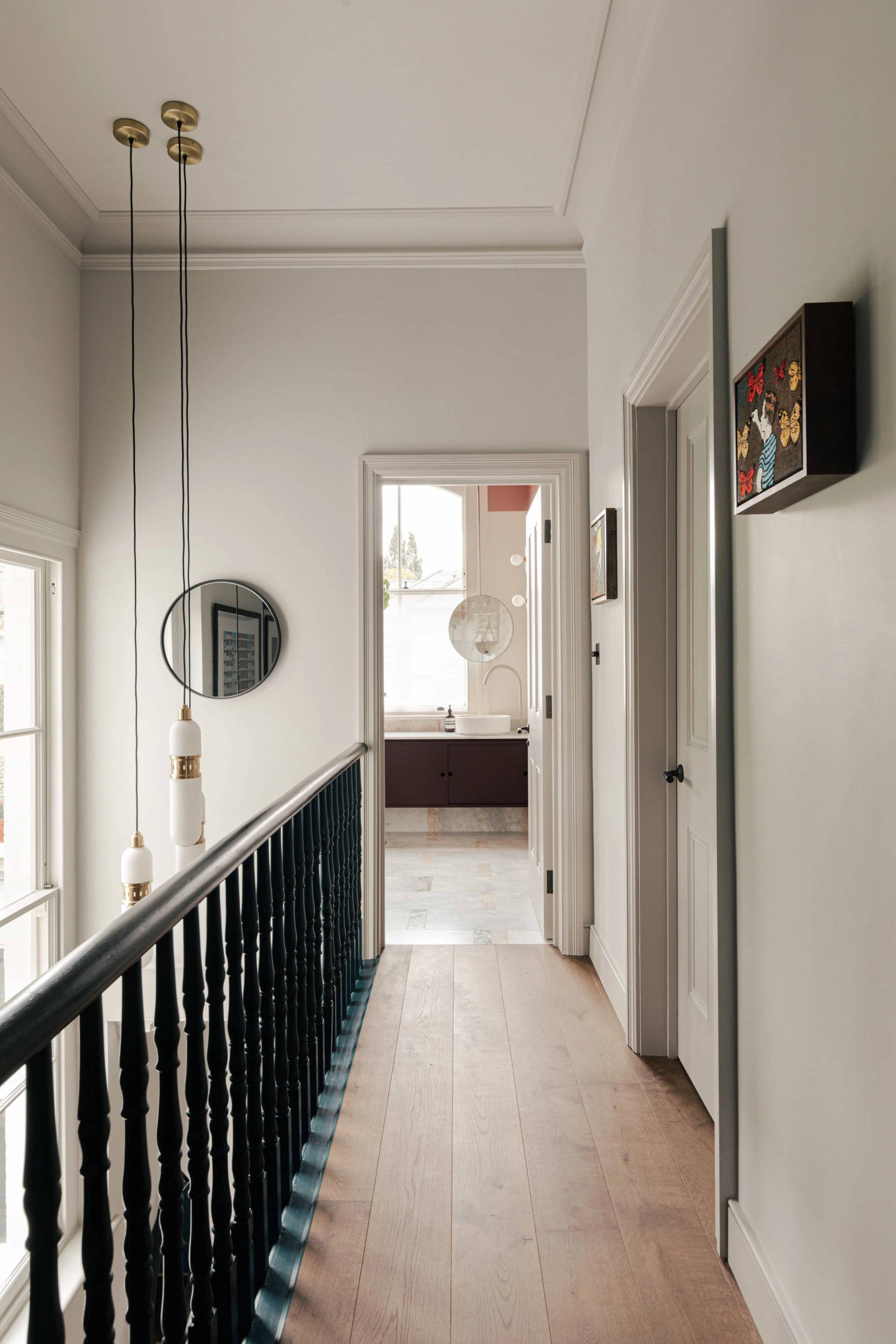Light-filled stairwell landing with black banisters and neutral walls, perfect for period drama scenes, Love Locations SW13.