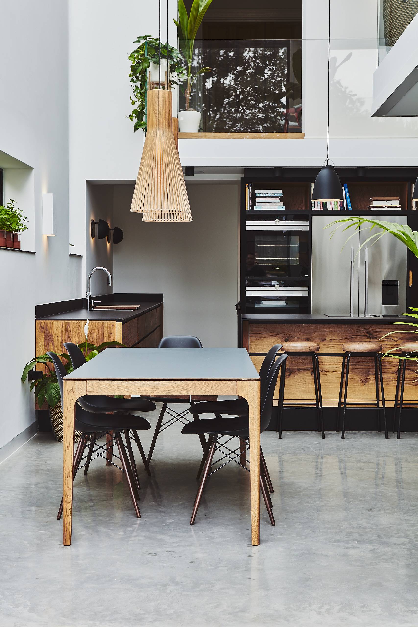 Sunlit kitchen dining space with a grey table, black chairs, and reclaimed wood island counter, Love Locations TW1.