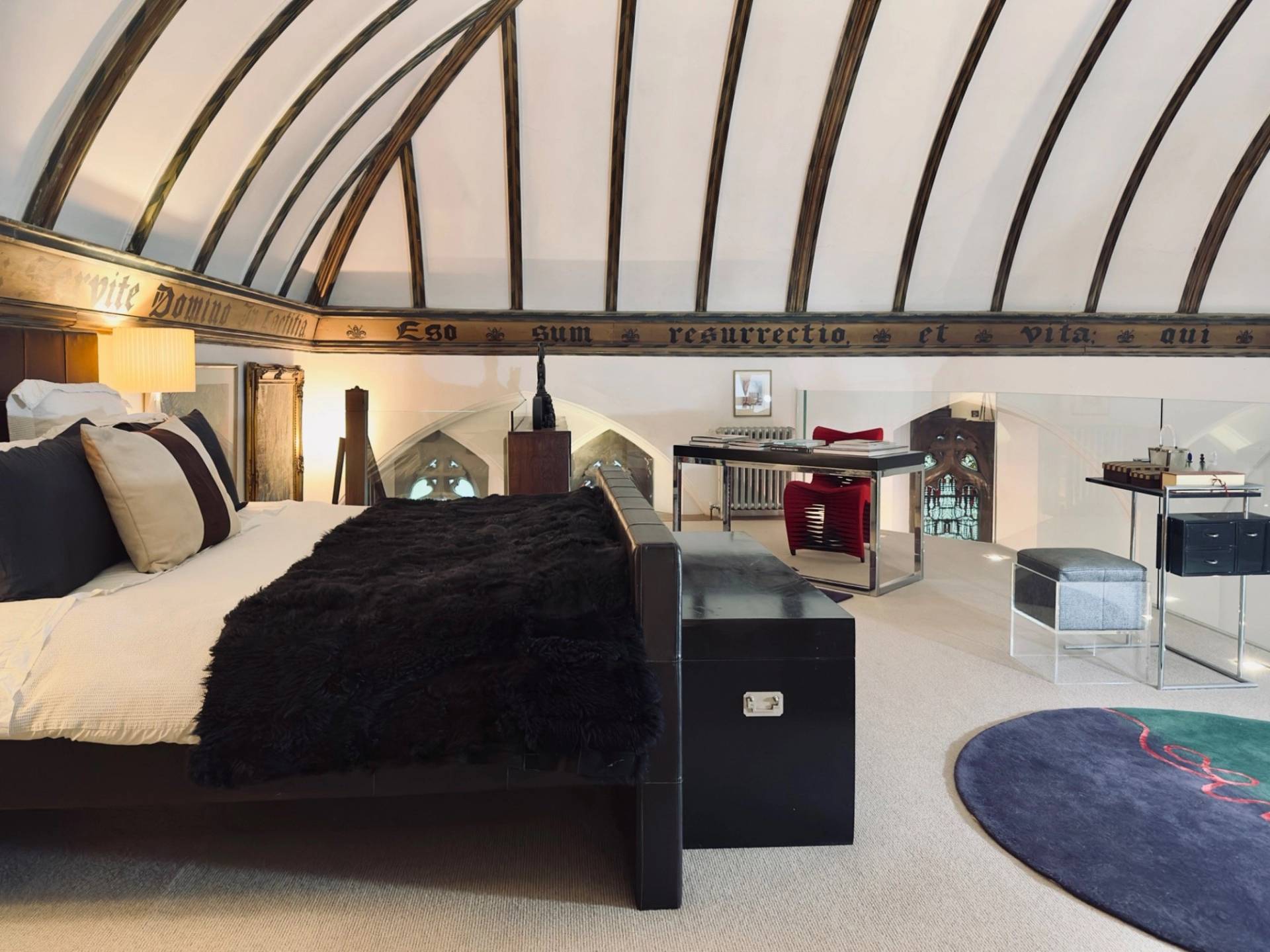 Vaulted attic bedroom film location in Oval SE5 via Love Locations, showcasing exposed roof timbers, a dark wood bed frame, and soft lighting.