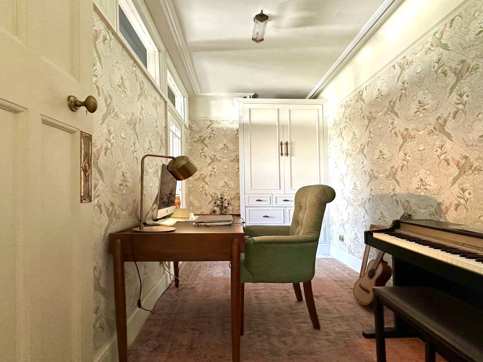 Home office study room with wooden desk, green armchair, piano, and textured wallpaper, Love Locations N13.