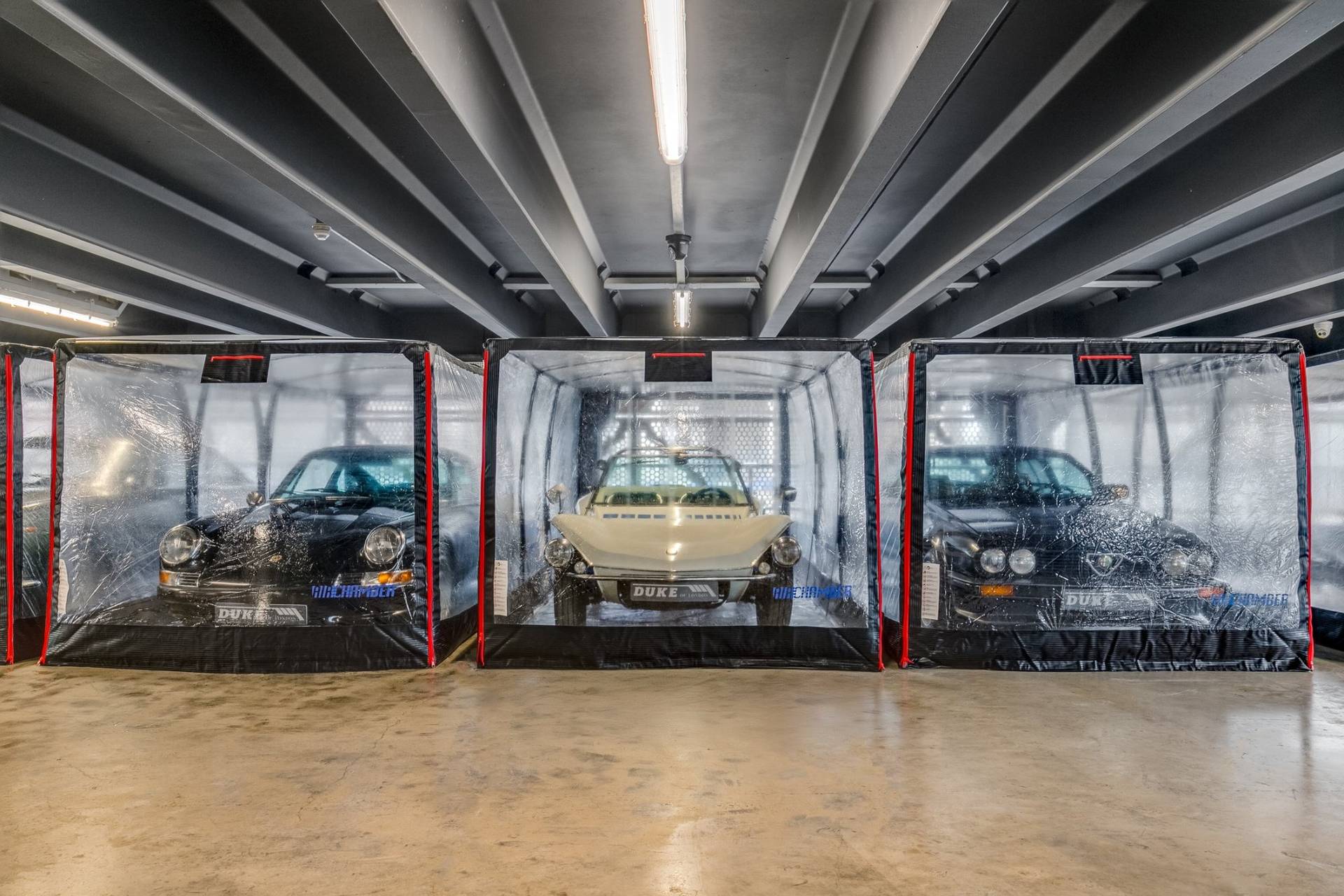 Symmetrical view of classic cars housed in clear inflatable storage capsules inside a Brentford showroom from Love Locations.