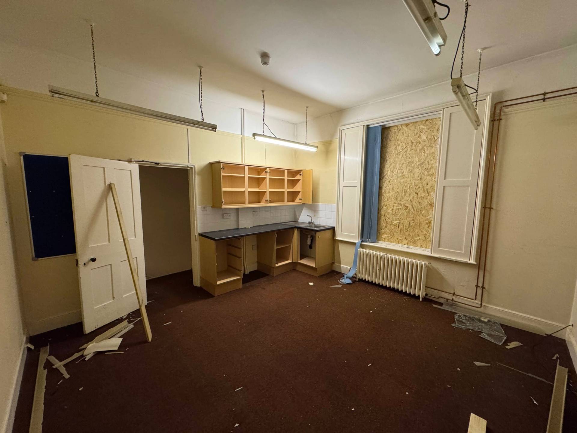 Alternate view of a distressed institutional kitchen workspace with traditional window shutters and radiators, Love Locations.