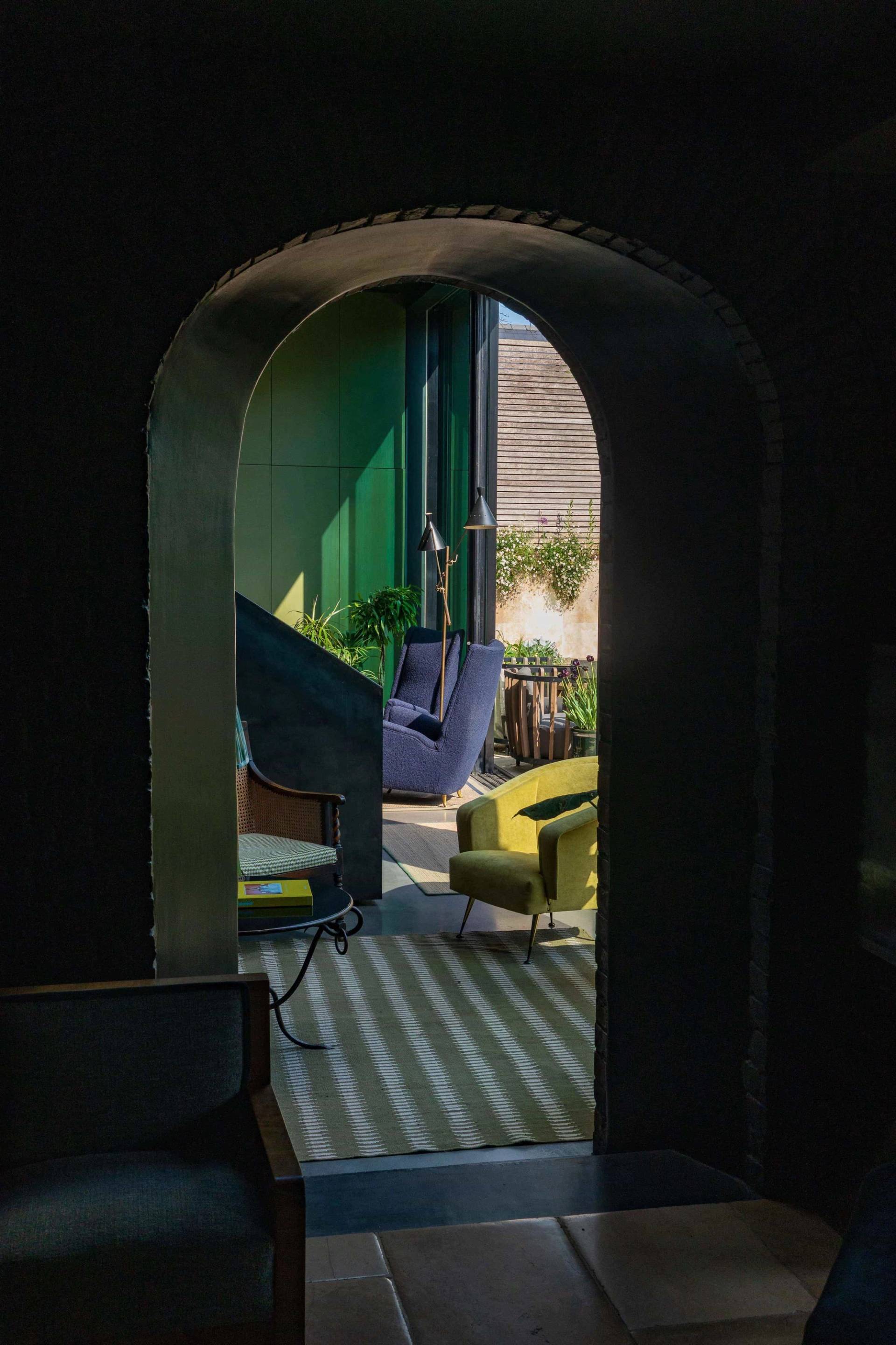 Moody dark corridor looking through a brick archway into a bright sunlit lounge area, perfect for cinematic film scenes, Love Locations.