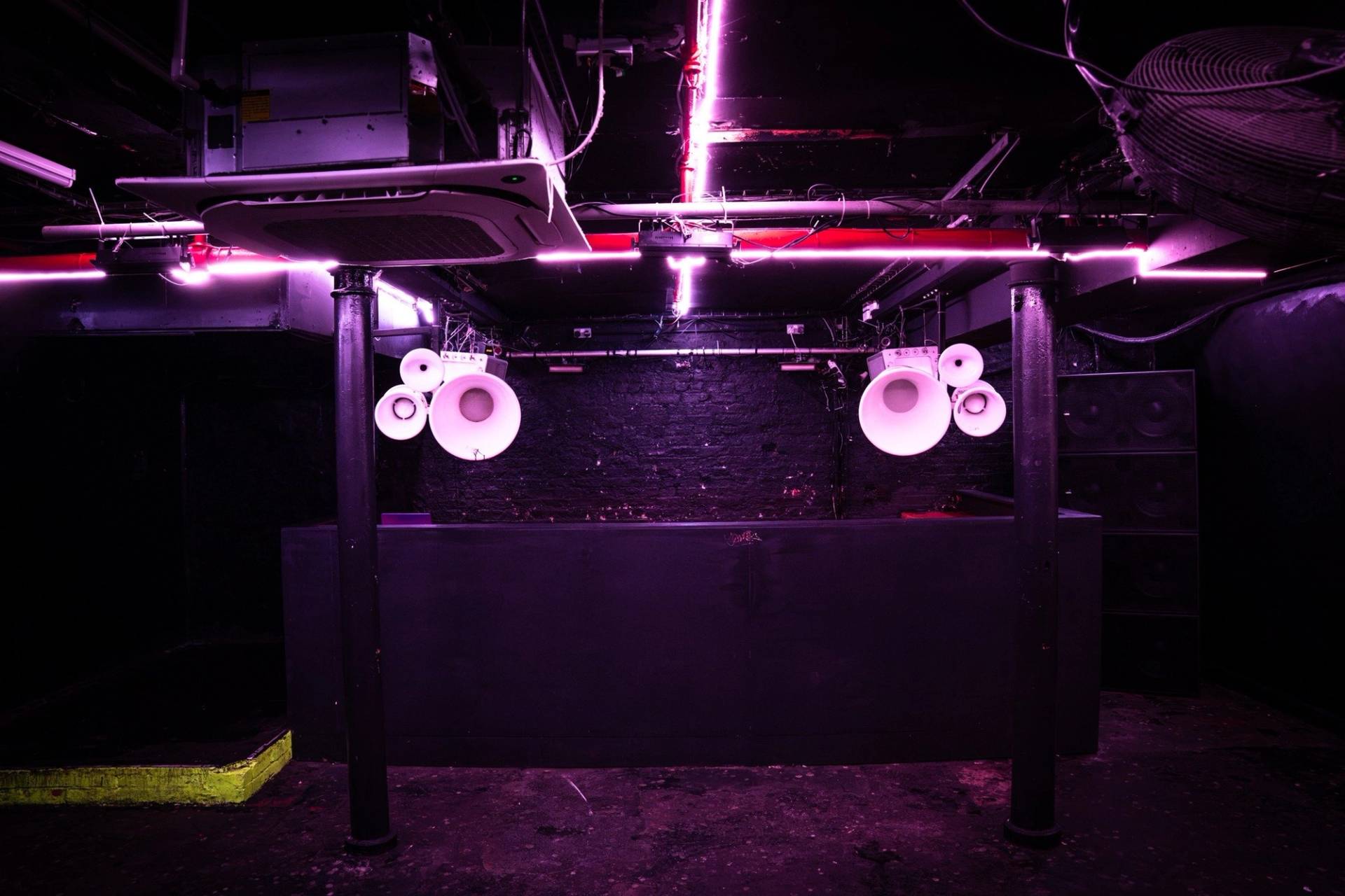 DJ booth enclosure equipped with horn speakers and ultraviolet purple lighting in a Manchester M3 location house via Love Locations.