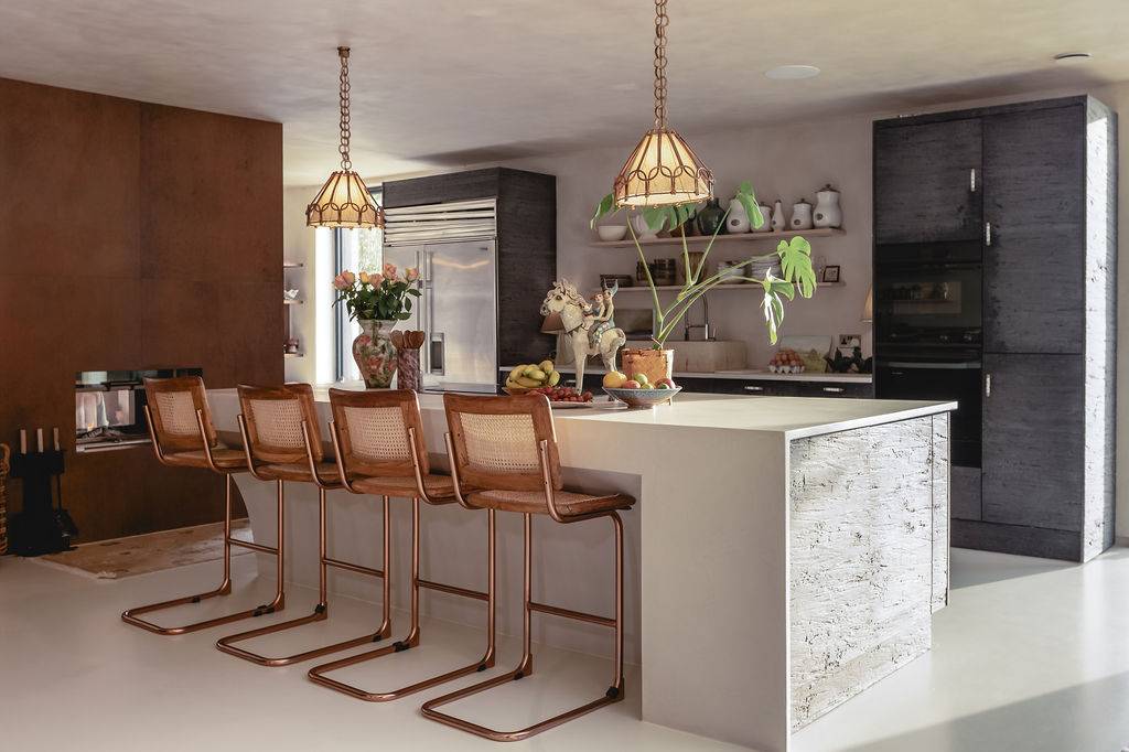 Sleek kitchen island counter featuring a veined marble waterfall top, rattan bar stools, and brass pendant lights, Love Locations GU32.