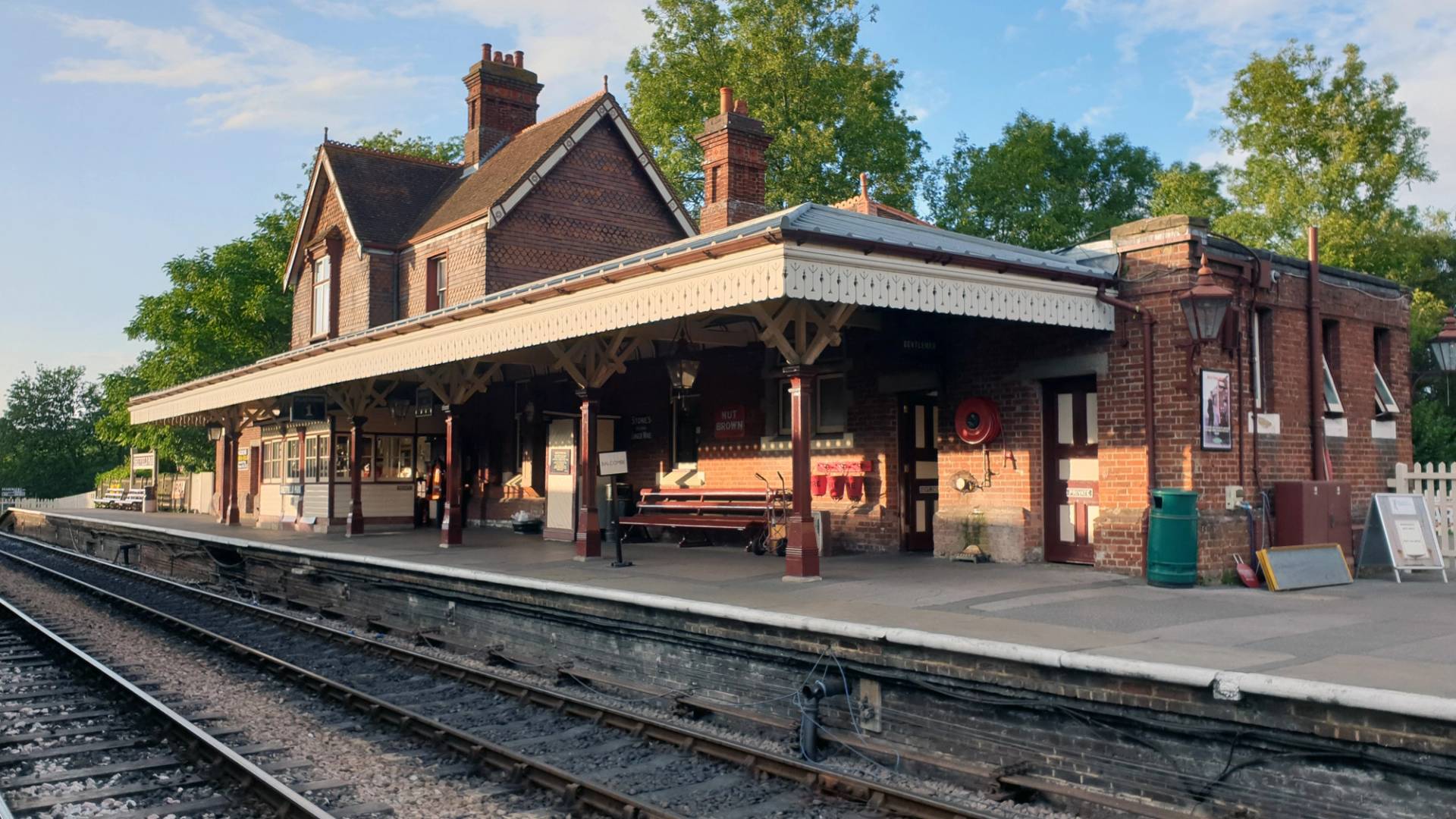 Victorian railway station platform featuring red brick buildings, green canopy pillars, and stone paving, ideal for TV period drama scenes, Love Locations TN22 3QL.