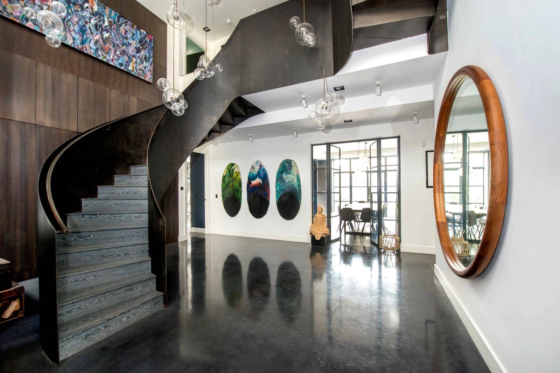 Grand architectural entrance hallway in Belsize Park, NW3 featuring a sweeping dark curved staircase, polished dark floors, and minimalist art display, ideal for luxury brand commercials via Love Locations.