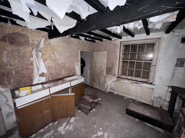 Dismantled room featuring hanging strips of peeling wallpaper, dark beams, and a retro cabinet, unique abandoned shoot location by Love Locations.