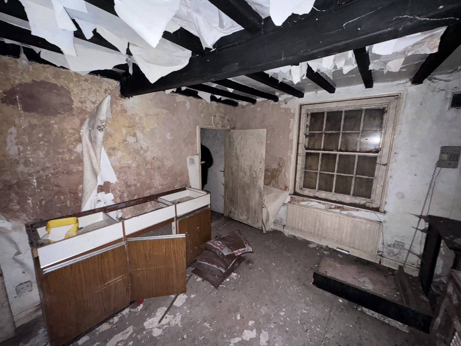 Dismantled room featuring hanging strips of peeling wallpaper, dark beams, and a retro cabinet, unique abandoned shoot location by Love Locations.