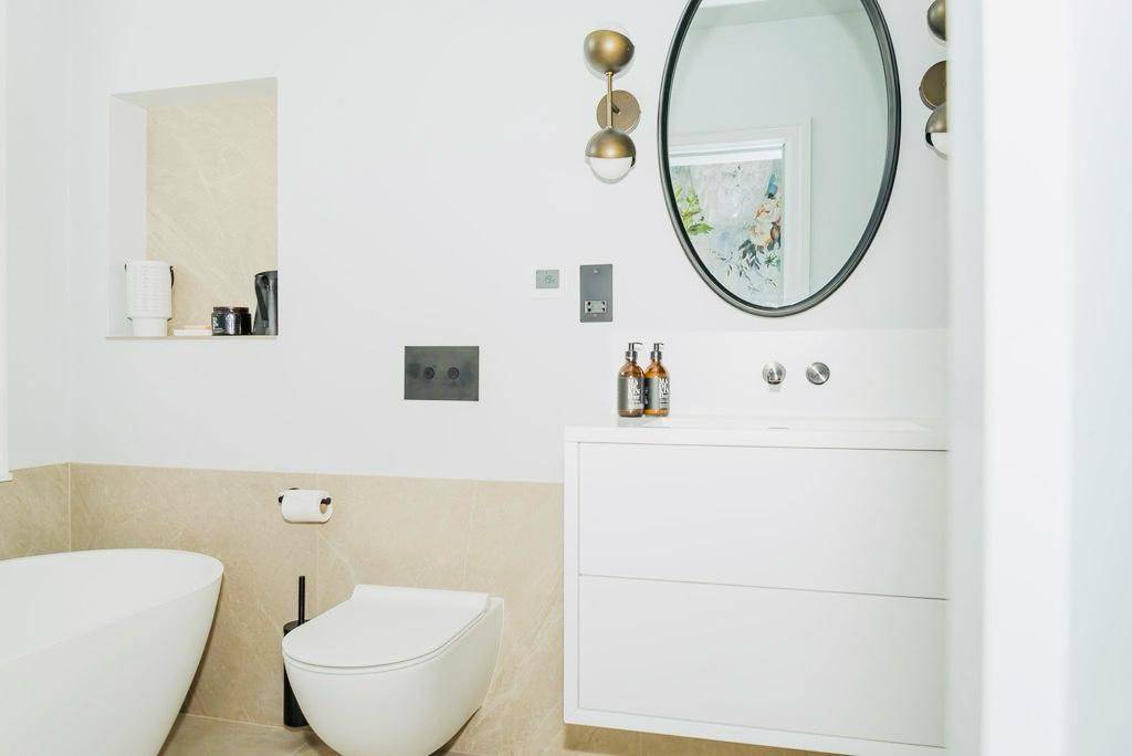 Modern wall-hung WC toilet and concealed cistern set against neutral bathroom walls, Love Locations TW11.