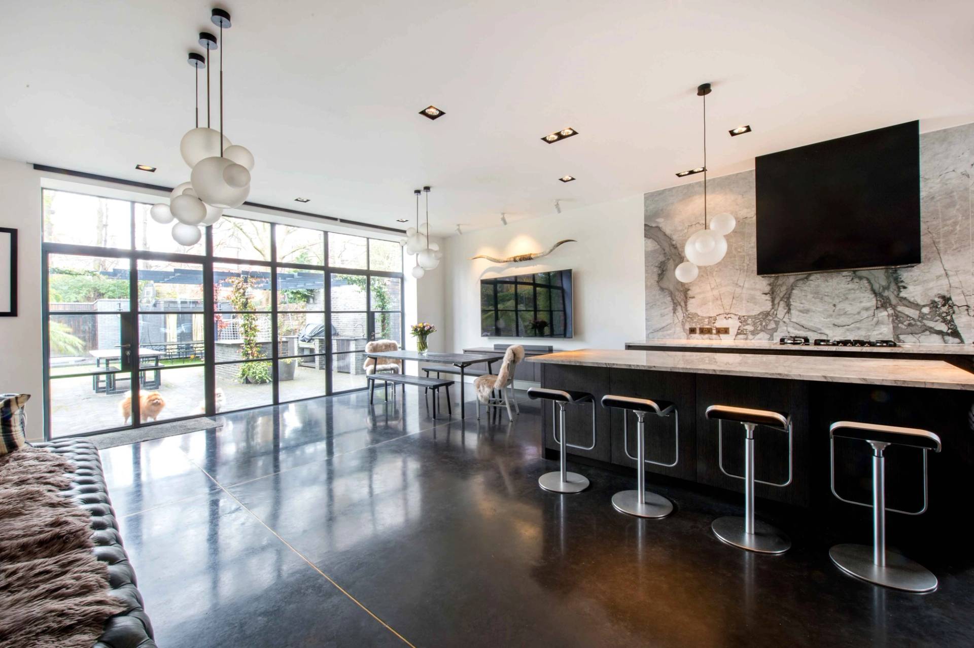 Wide view of a luxury kitchen and casual seating zone with polished dark floors, ideal for lifestyle commercial filming via Love Locations.