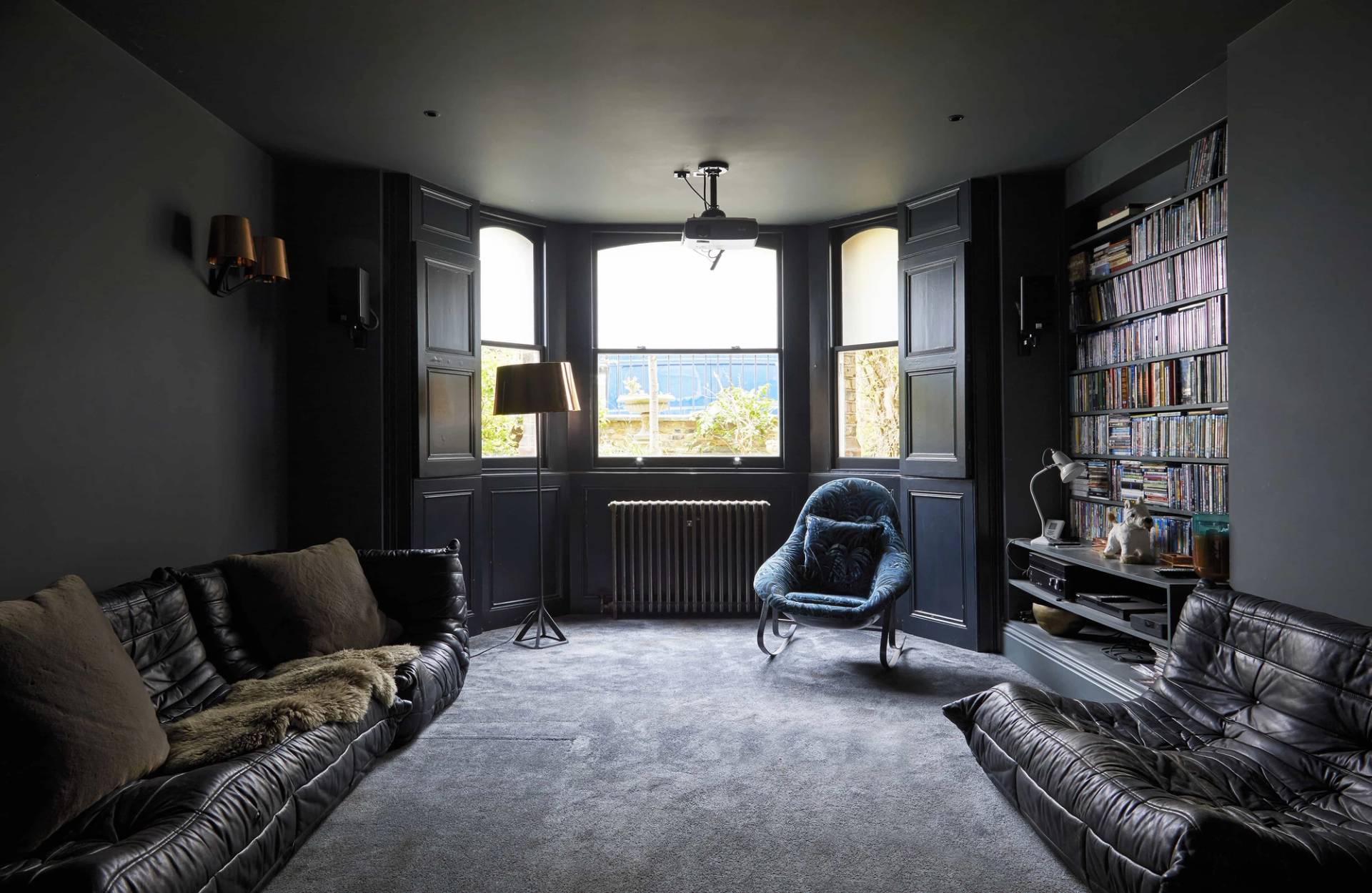 Dark moody cinema room in Finsbury Park, N16 featuring deep grey walls, bay window, black leather sofa, and carpet, Love Locations.