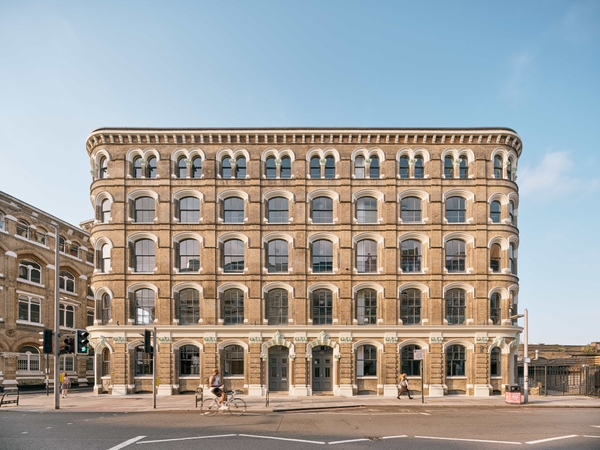  The Lounge SE1 exterior front facade showing a classic brick warehouse building with large arched windows and a bright blue sky.