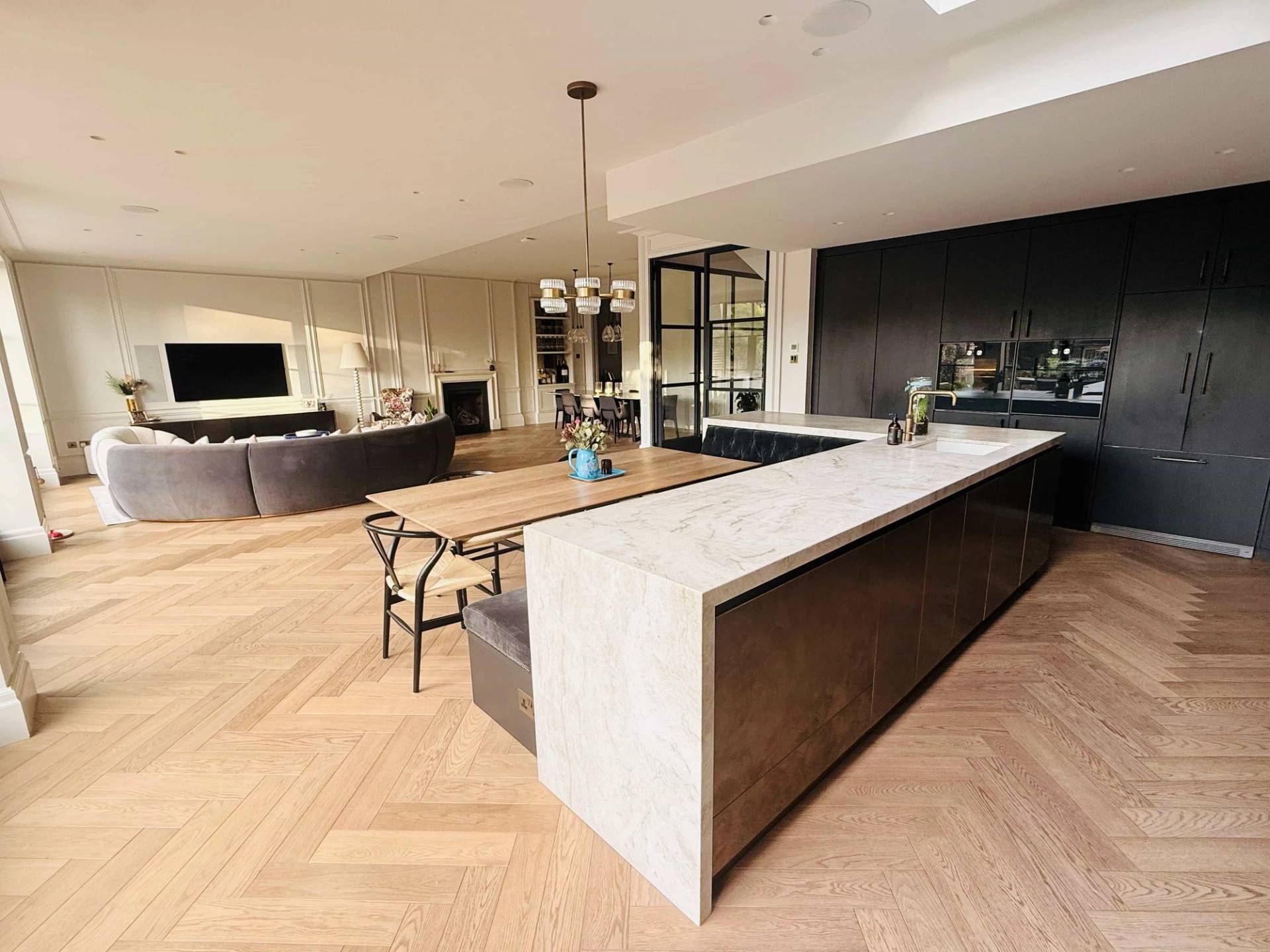 Wide kitchen island with waterfall marble edges and herringbone parquet timber floorboards, Love Locations TW11.
