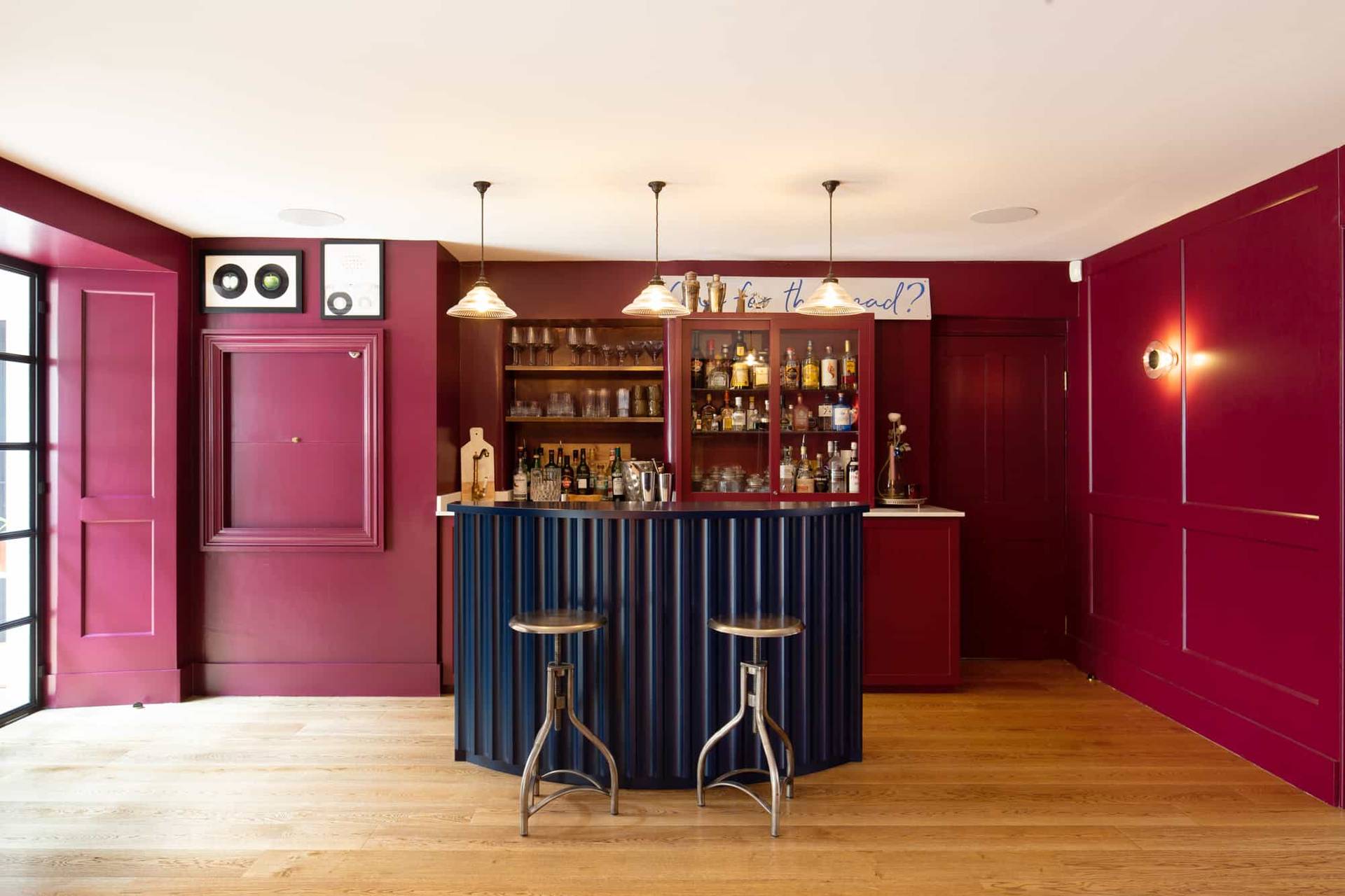 Home bar shoot location in Camberwell, SE5 featuring fluted island counter, brass bar stools, and plum painted walls via Love Locations.