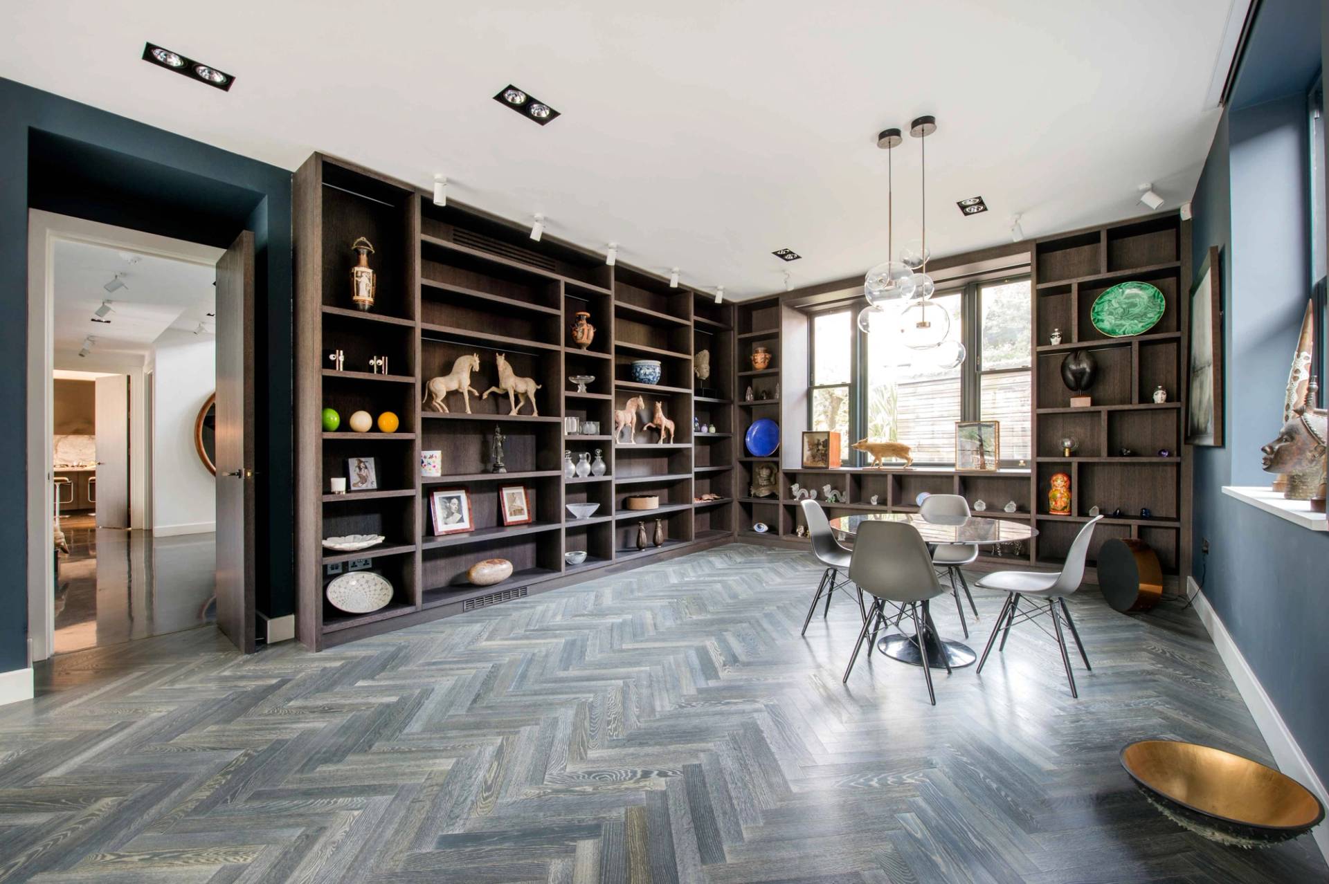 Expansive open-plan living area featuring a floor-to-ceiling built-in dark wood bookcase and display shelving, Love Locations.