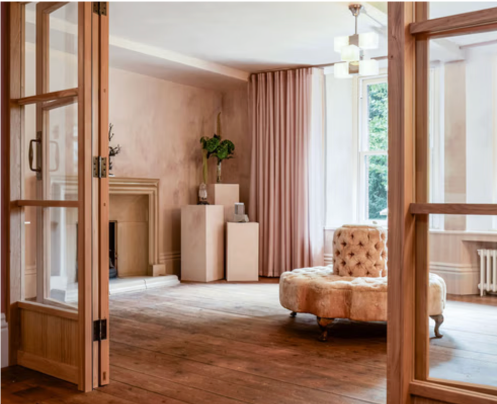 Soft blush reception room at Fable with textured plaster walls, timber floors and elegant pink furnishings.