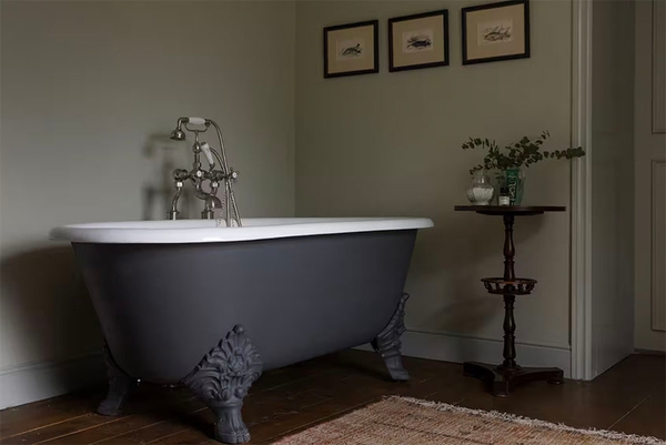 Freestanding claw-foot bath in a Glenstriven house bathroom, dark wood floor and soft neutral walls.