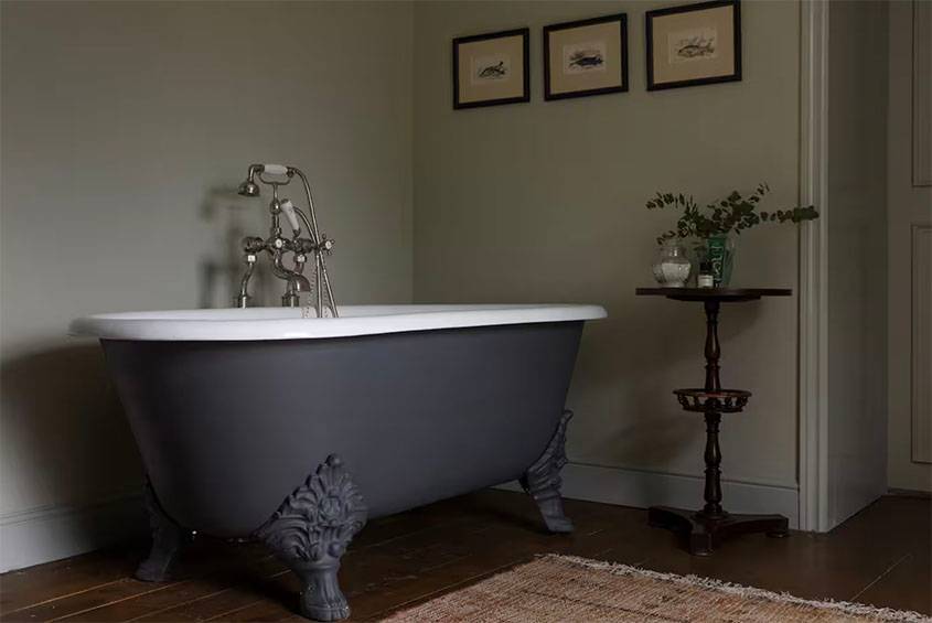 Freestanding claw-foot bath in a Glenstriven house bathroom, dark wood floor and soft neutral walls.