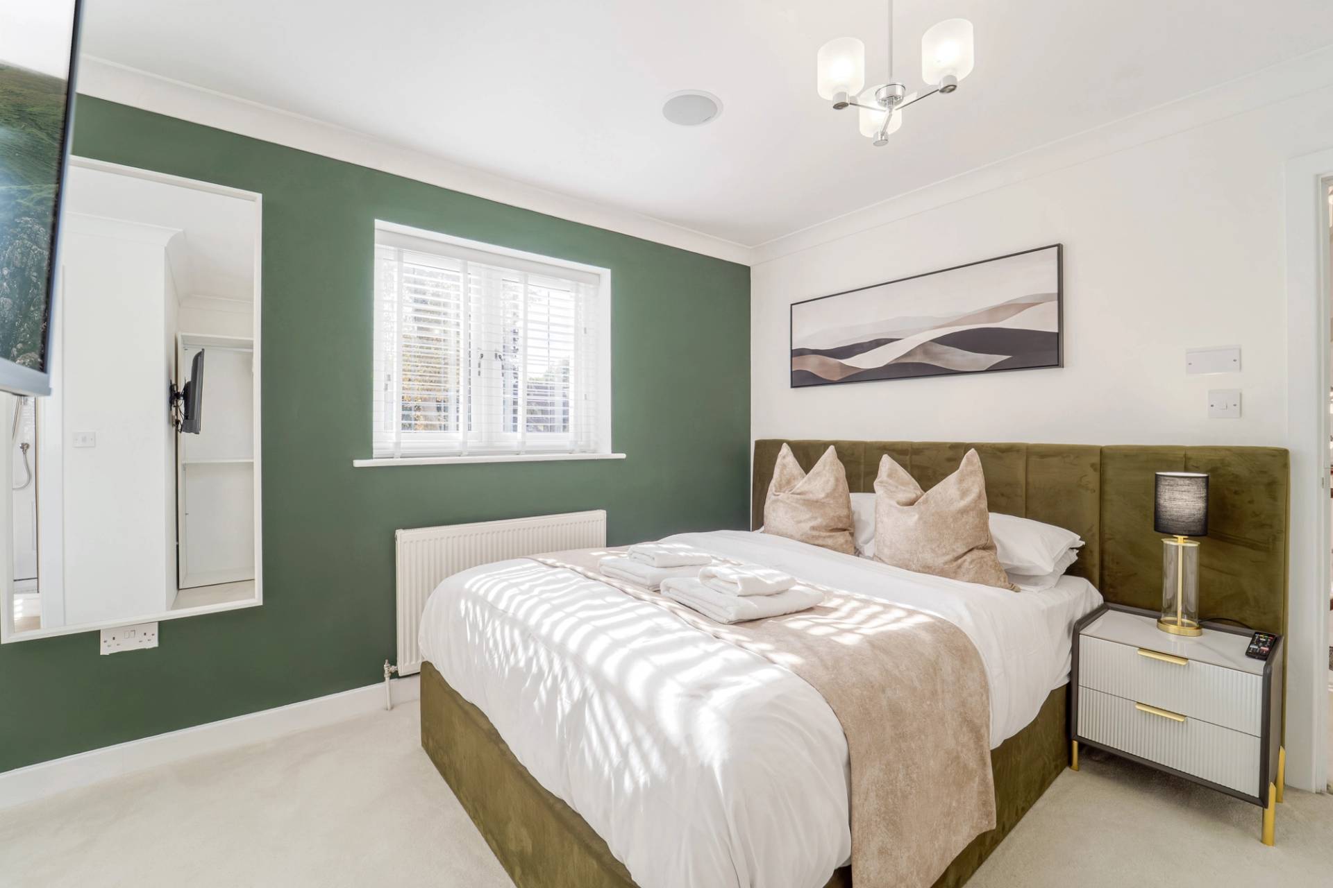 Guest bedroom featuring a green accent wall, upholstered bed, and sash window light, Love Locations RM11.