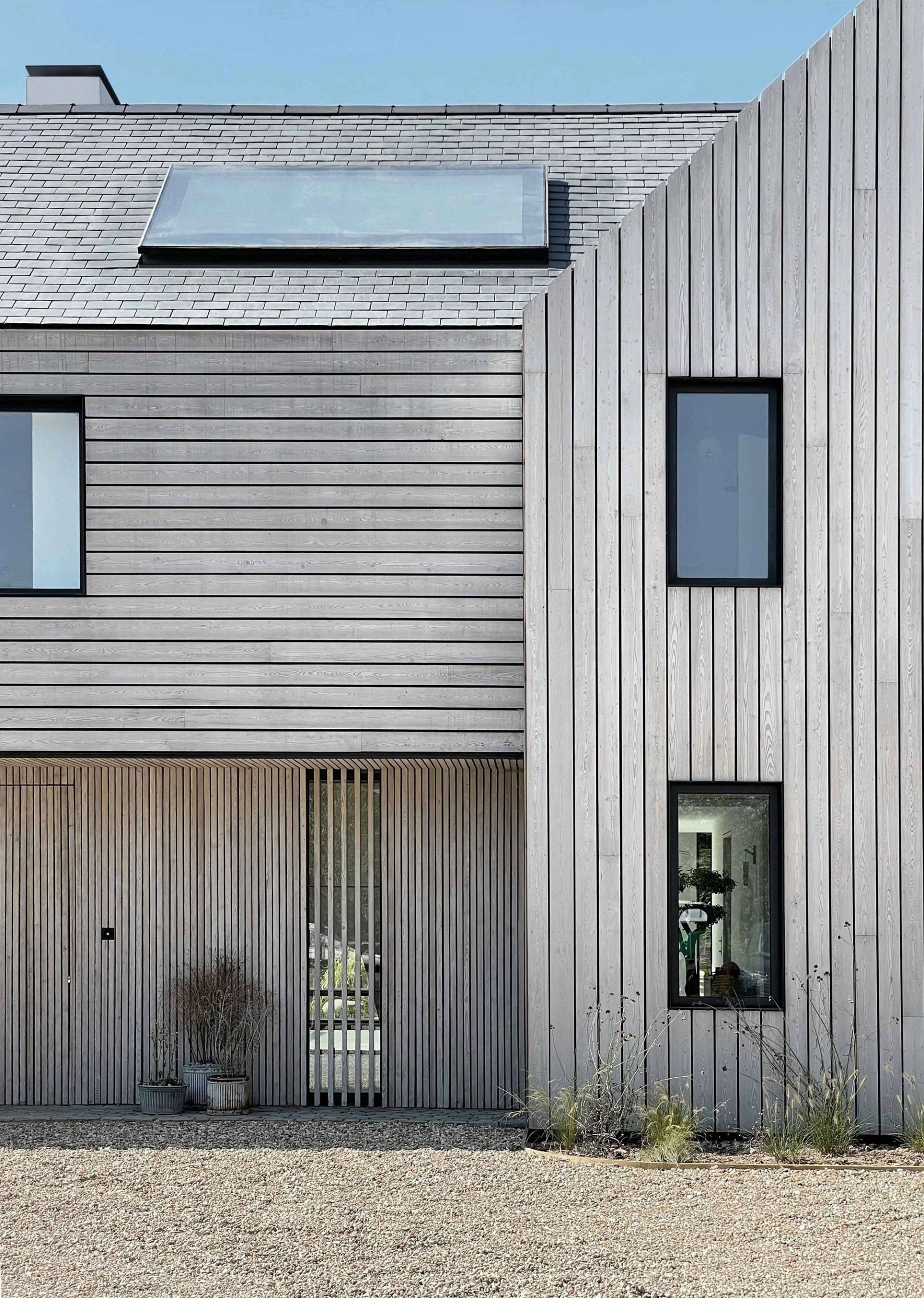 Detailed architectural exterior view of vertical timber cladding, flint masonry work, and dark window frames on a contemporary West Sussex estate, the ultimate hero backdrop for automotive commercials, editorial campaigns, and film productions via Love Locations.