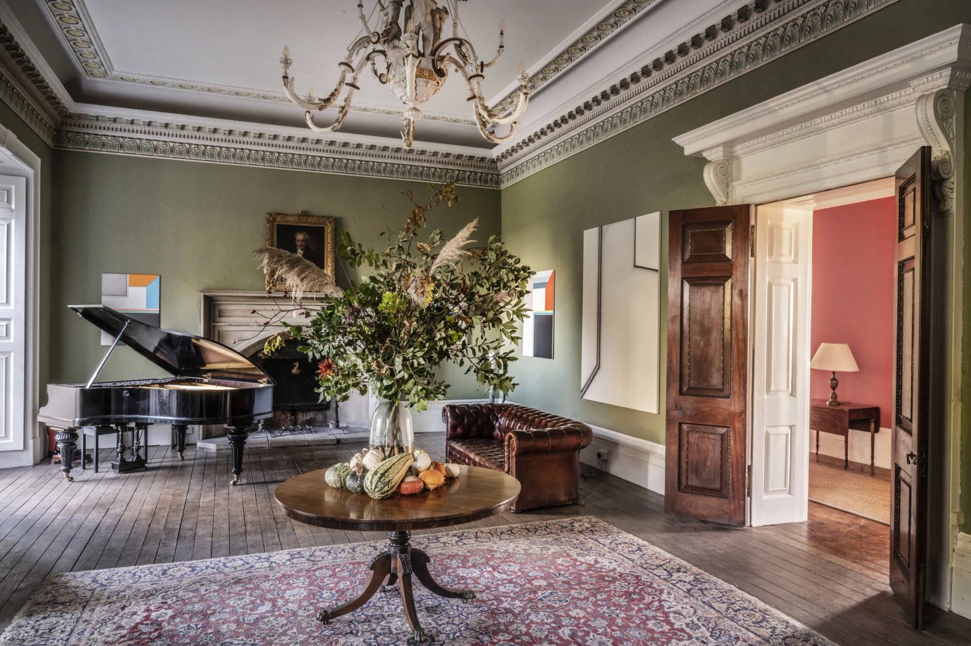 Grand sage green reception room with intricate ceiling cornicing, a central tilt-top table, and a grand piano in Tugby, Leicestershire, perfect for high-fashion editorials, Love Locations LE7.