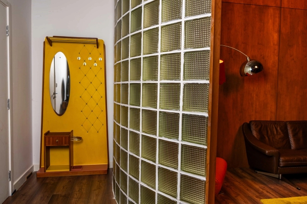Curved glass block wall divider set against wood panelling and a yellow vanity set in a studio space, Love Locations N15.