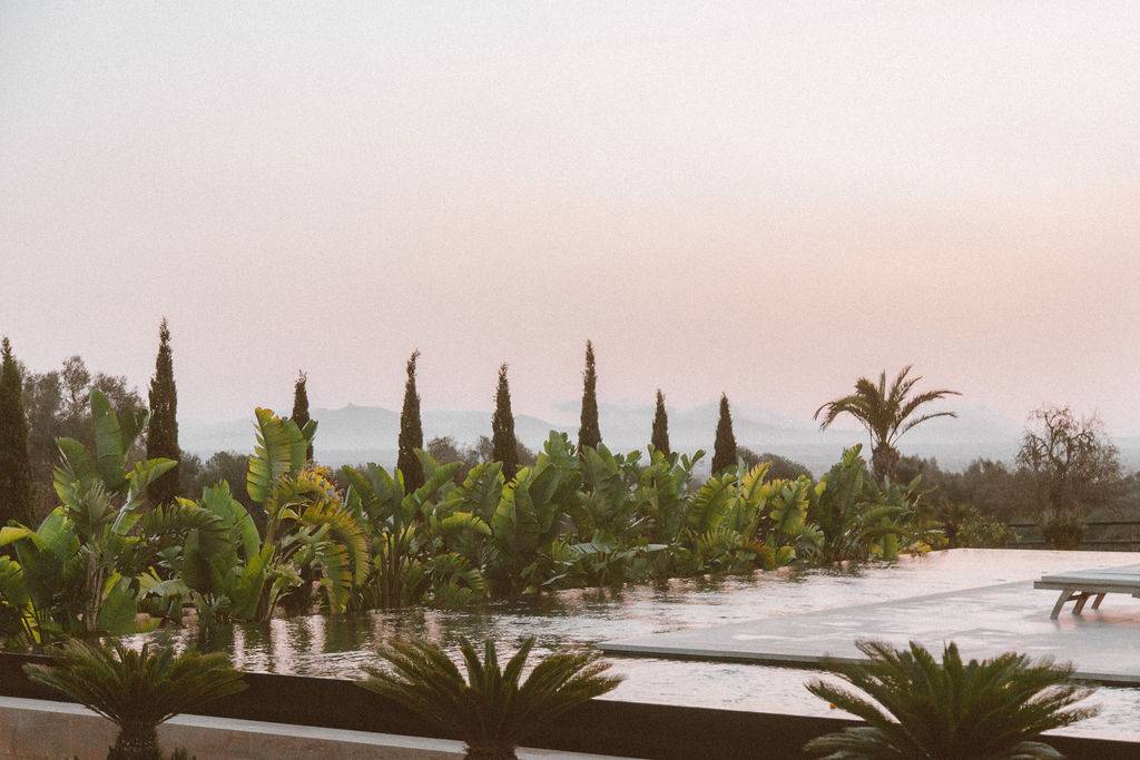 Infinity edge swimming pool overlooking lush palm trees and rural countryside landscapes, Love Locations 07630.