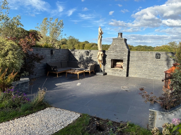 Enclosed outdoor stone patio film location with an integrated stone fireplace structure and gravel pathways, managed by Love Locations.